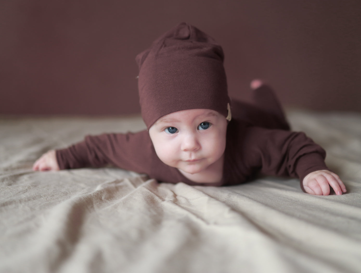 Baby mit Beanie aus Kaschmir-Mix von petit cochon liegt zufrieden auf dem Bauch