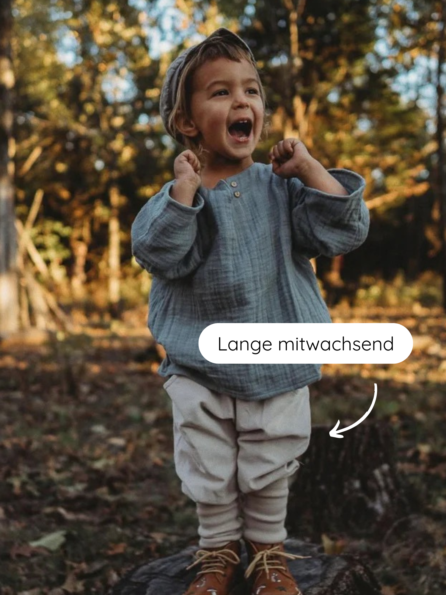 Knickerbocker Feincord - Sand: Ein Kleinkind steht auf einem Baumstumpf, trägt eine beige Feincordhose mit elastischen Bündchen und braunen Stiefeln. Die Hose wächst mit und bietet Bewegungsfreiheit.