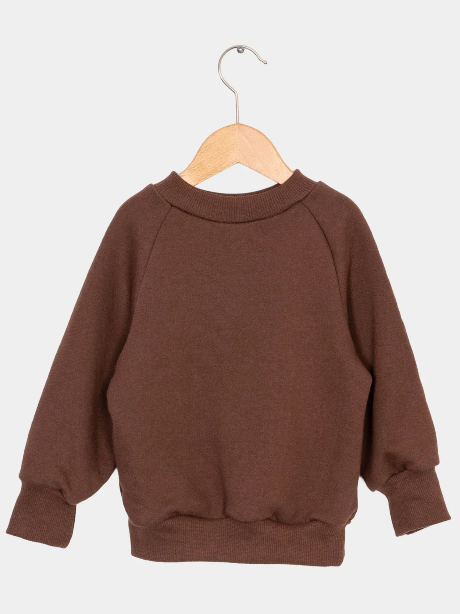 Pulli Bio-Sweat - Schoko: Ein schlichter brauner Crewneck-Pullover aus Bio-Sweat, hängt an einem Holzkleiderbügel. Ideal für Kinder, mit weichem, angerautem Stoff und breiten Bündchen.