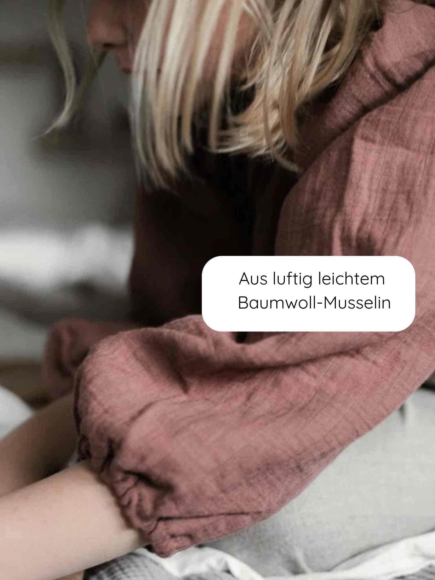 Nahaufnahme einer Person mit blondem Haar, die eine Blüschen Musselin - Malve trägt, mit ballonartigen Ärmeln aus luftigem Baumwoll-Musselin, ideal für warme Tage und empfindliche Kinderhaut.
