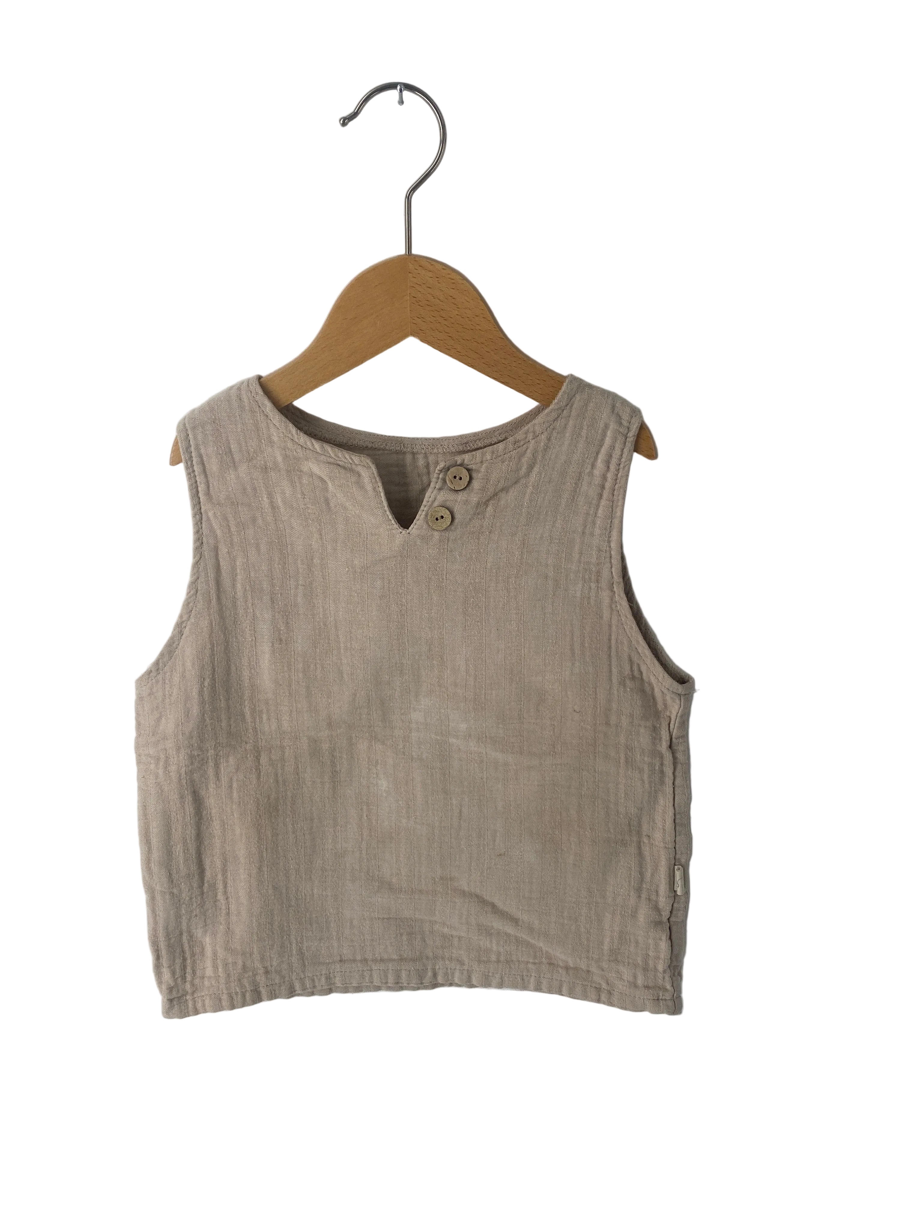 Ärmelloses Musselin-Top Sand Gr 2Y, aus hellem Stoff, mit kleinem V-Ausschnitt und zwei runden Holzknöpfen. Zustand: gut, mit leichten Flecken, präsentiert auf einem Holzkleiderbügel.