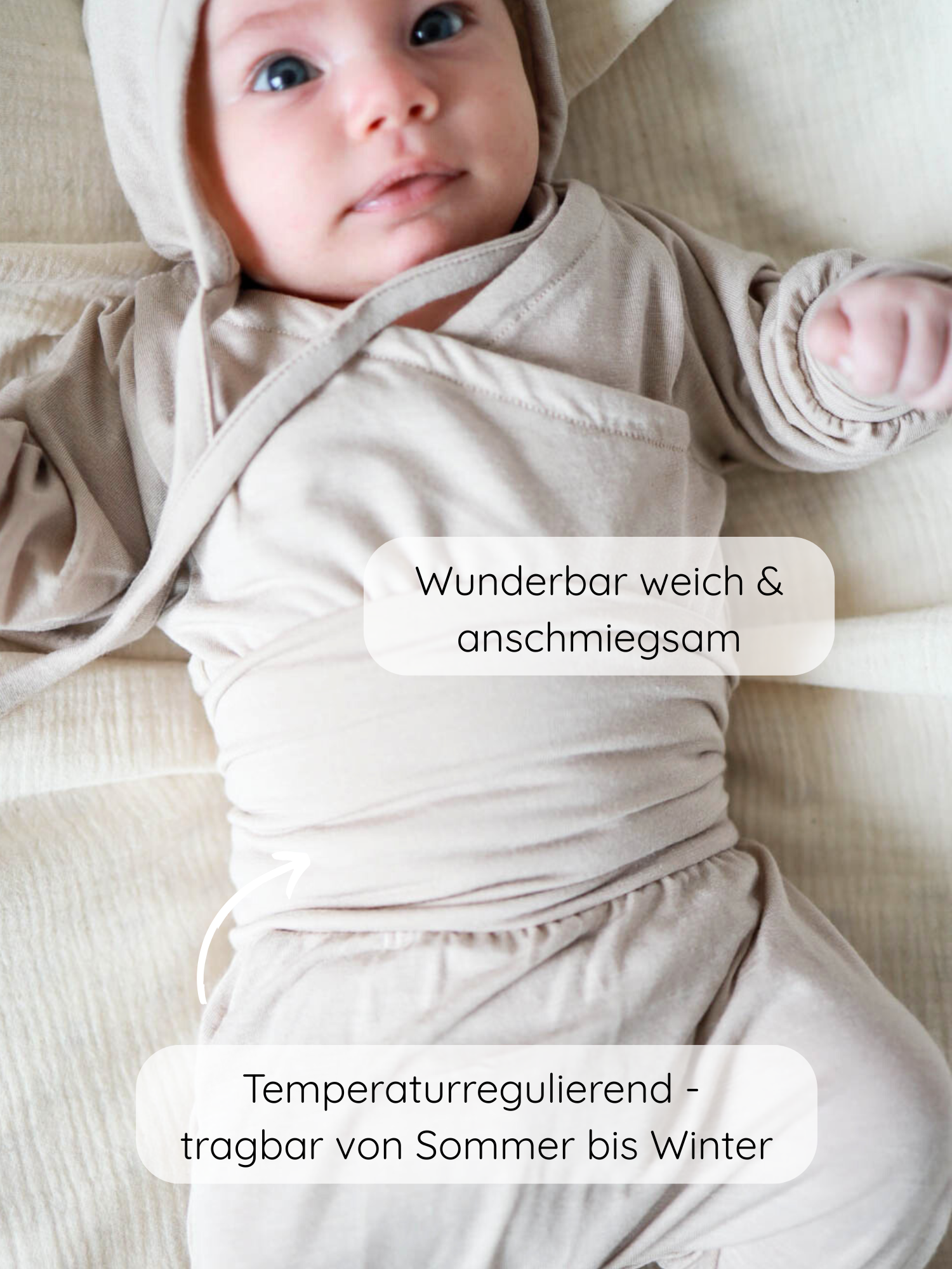 Neugeborenes in einem Loopbody Kaschmir-Mix - Sand, langärmlig, mit Kapuze, auf weicher beige Fläche liegend. Der Body ist wunderbar weich, anschmiegsam und temperaturregulierend für Sommer bis Winter.