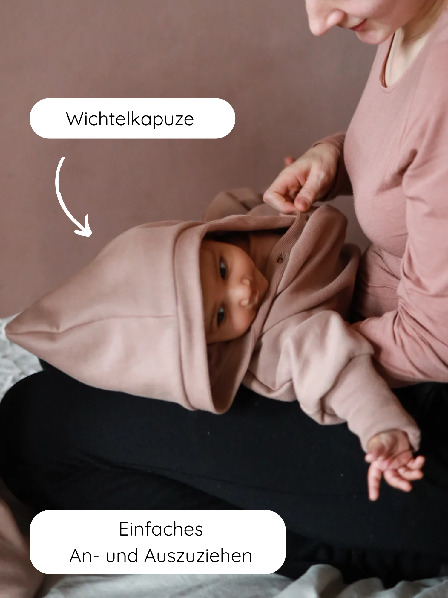 Eine Mutter hält ihr Baby, das einen Kuschelanzug Bio-Sweat - Puder mit Wichtelkapuze trägt. Der Anzug betont einfaches An- und Ausziehen und bietet kuscheligen Komfort aus Bio-Baumwolle.