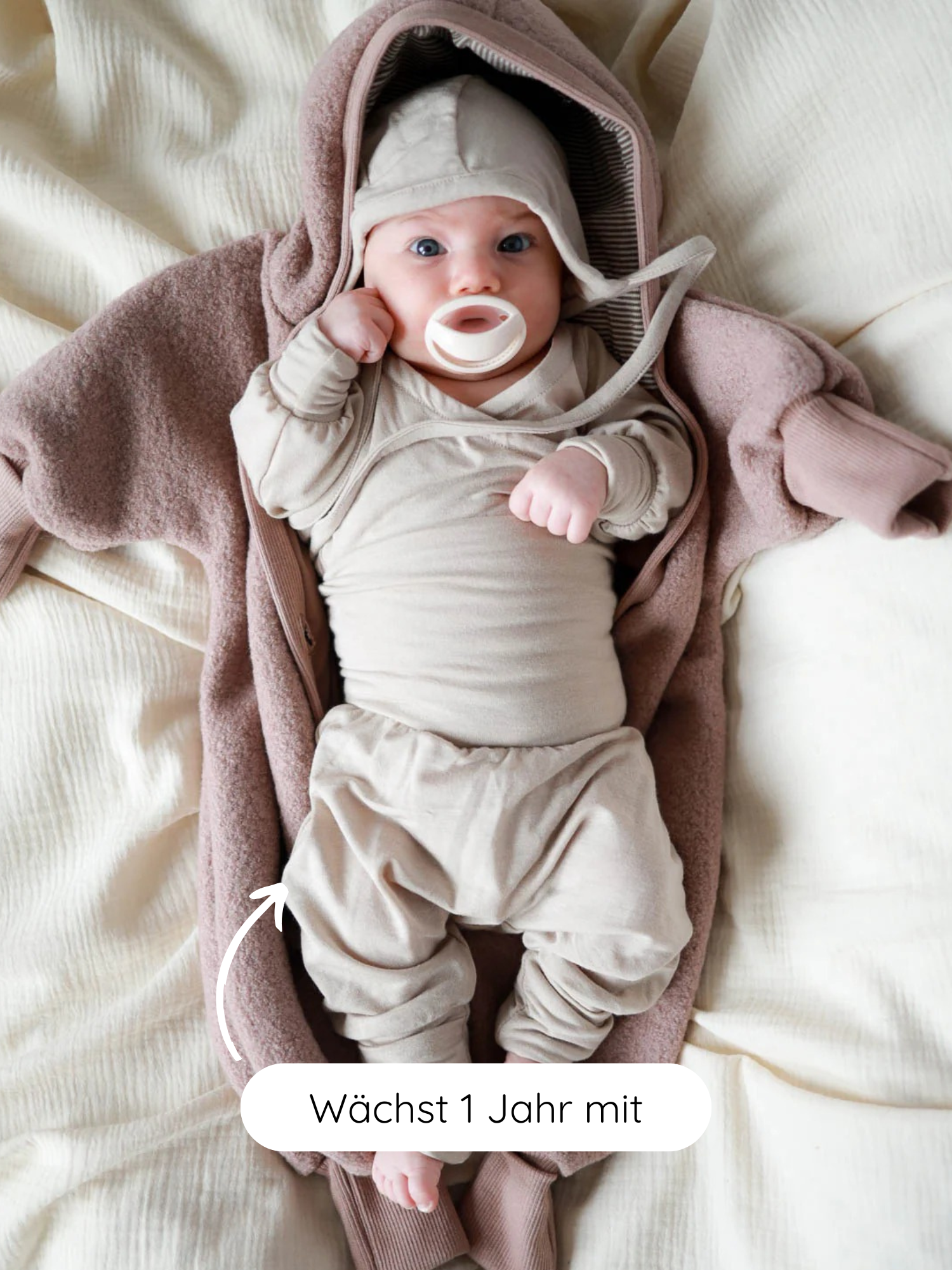 Ein Baby trägt den Loopbody Kaschmir-Mix - Sand, passend und bequem. Der Body wächst bis zu einem Jahr mit, ohne Knöpfe, umhüllt den Bauch und bietet extra Wärme.