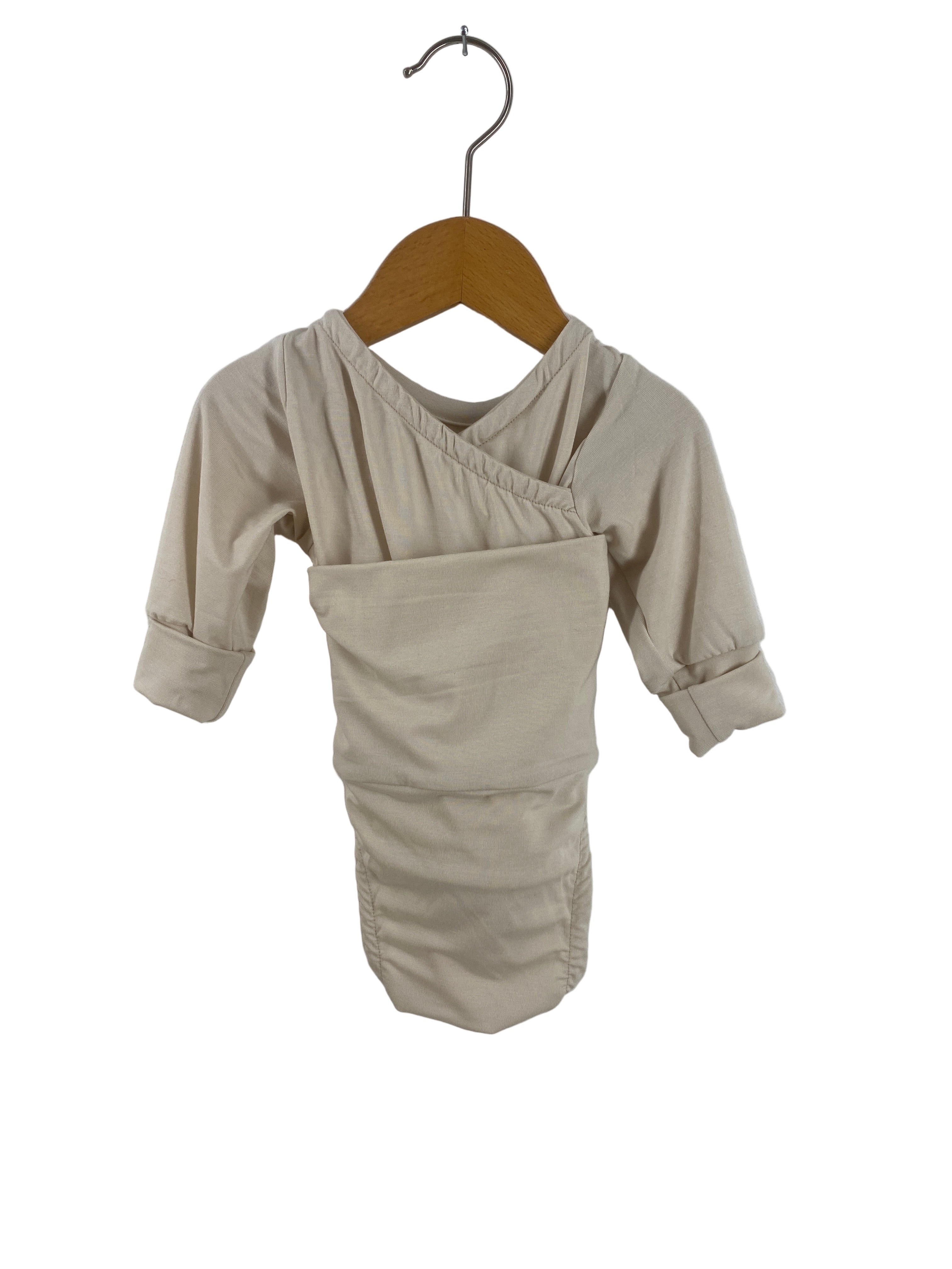 Beigefarbener Loopbody Tencel Creme Gr 0M, langärmelig im Wickelstil, hängt auf einem Holzkleiderbügel. Zustand: neu, mit weniger elastischen Loop- und Armbündchen, präsentiert auf neutralem Hintergrund.