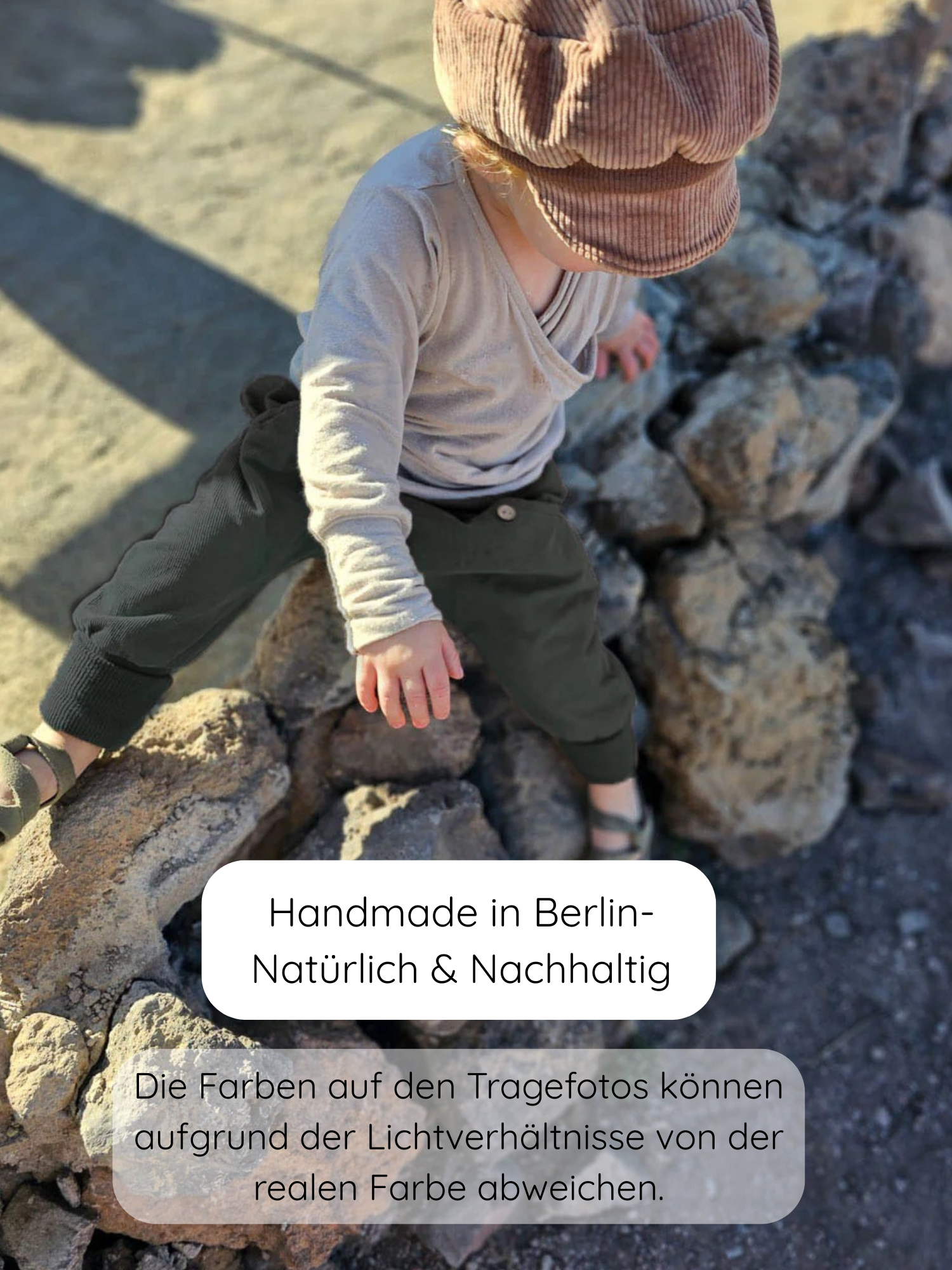 Kind sitzt auf Felsen, trägt Knickerbocker Feincord - Avocado: olivgrüne Hose aus weichem Baumwollcord, elastischer Bund, ideal für aktive Kinder. Kombiniert mit beigem Oberteil und brauner Mütze.