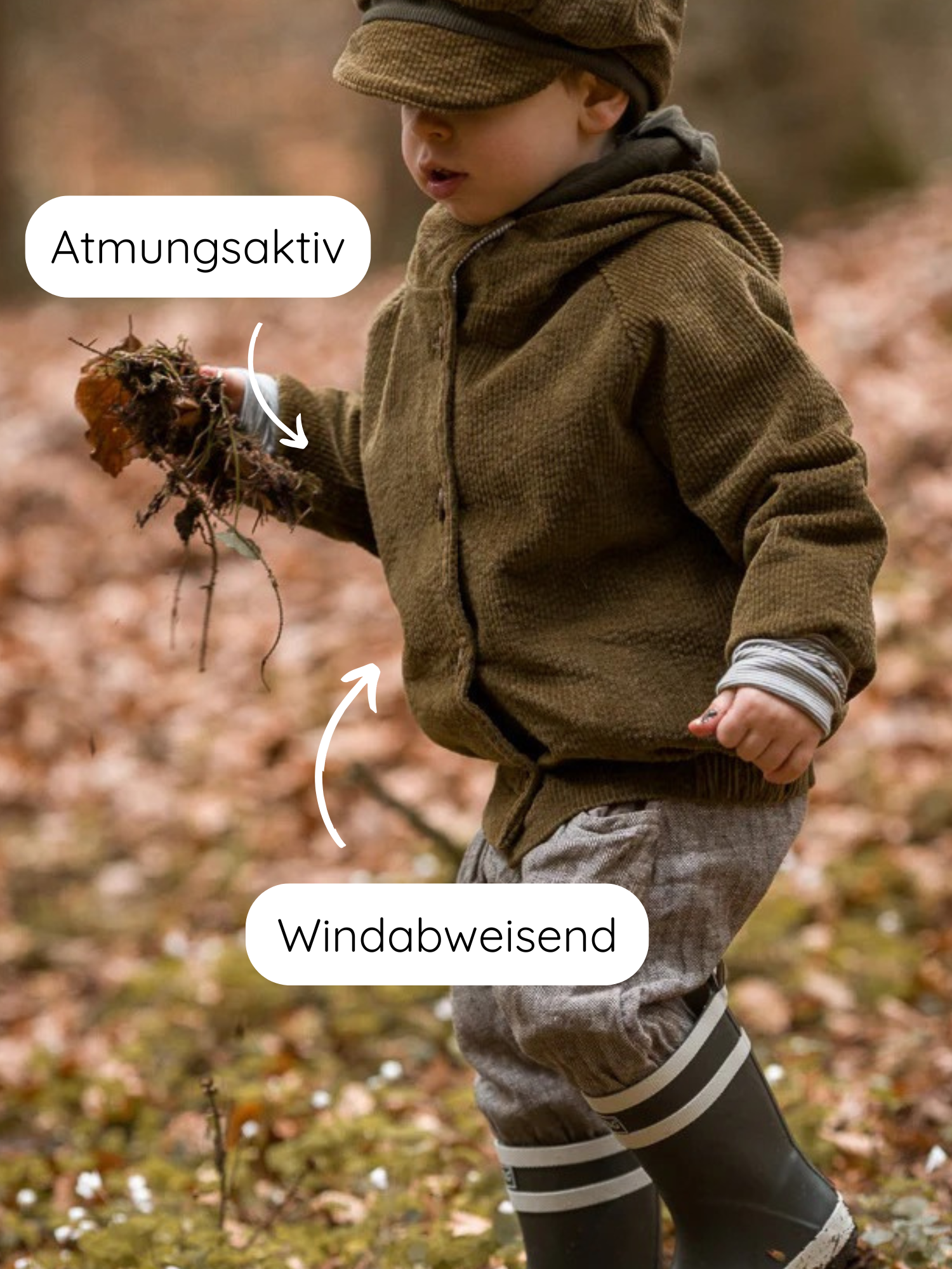 Ein Kleinkind trägt die Wichteljacke Breitcord Stretch - Kiwi mit einer Wichtelkapuze. Die Jacke ist atmungsaktiv und windabweisend, perfekt für Herbstabenteuer im Wald.
