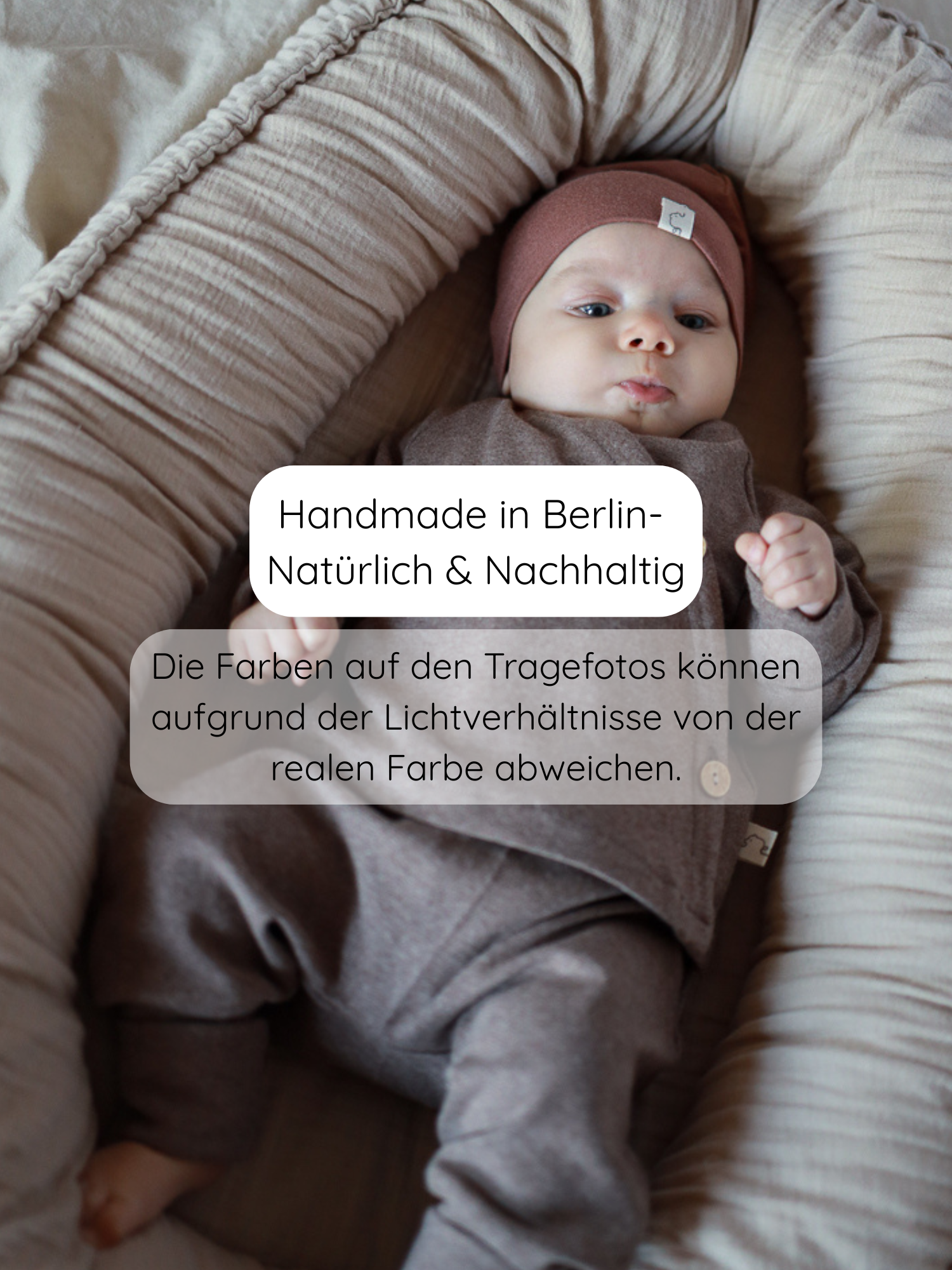 Baby in einem weichen, gepolsterten Baby-Nest Lounger, trägt einen Babyknicker Feinstrick - Praline Meliert. Handgefertigt in Berlin, aus elastischem, atmungsaktivem Feinstrick-Jersey, leicht anzuziehen und bietet Bewegungsfreiheit.