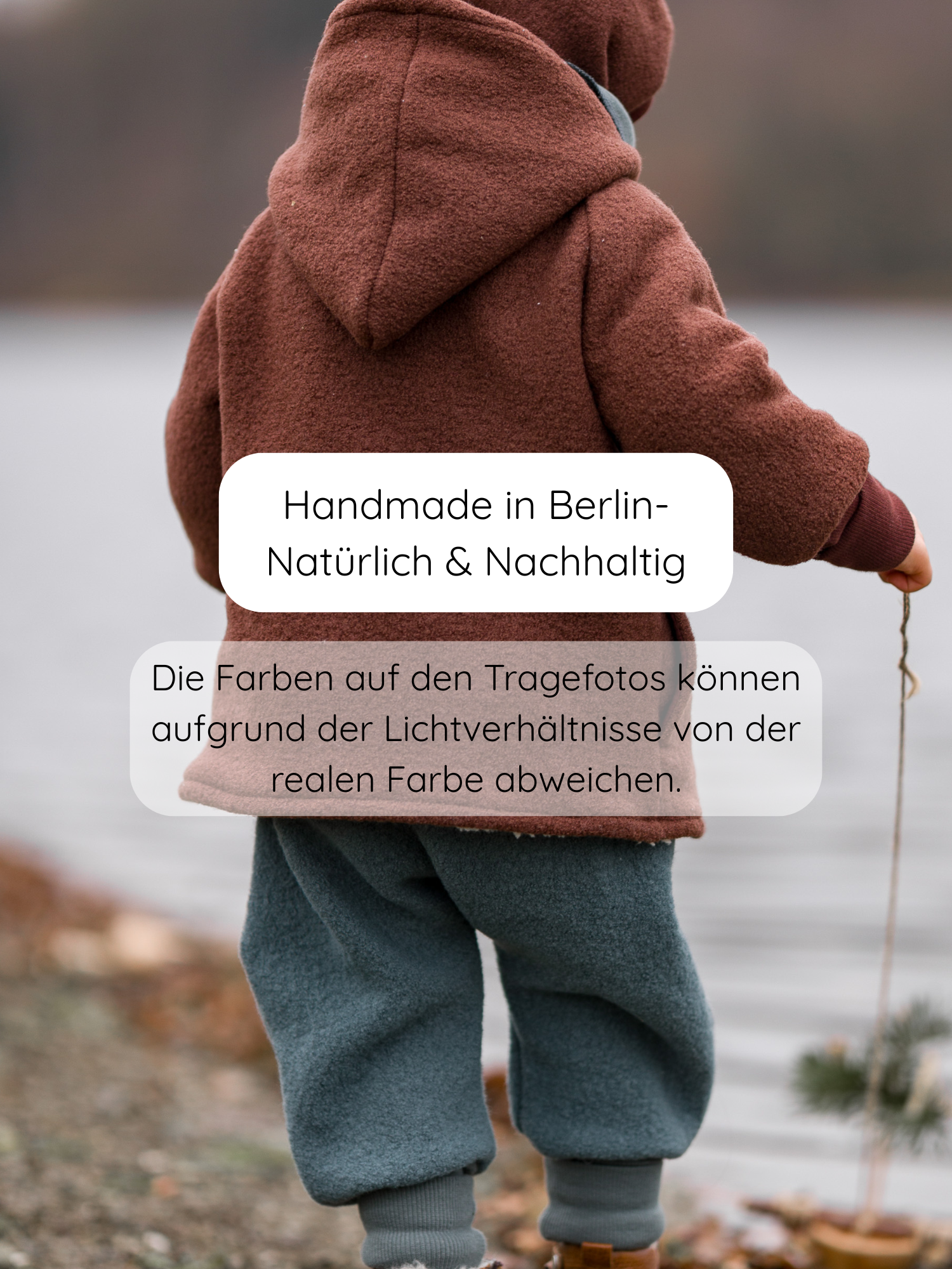 Kleinkind am See, trägt Knickerbocker Wollwalk - Taube: rustbraune Kapuzenjacke, schieferblaue Wollhose mit Krempelbündchen, braune Stiefel. Handgefertigt in Berlin, nachhaltig. Farbdarstellung kann variieren.