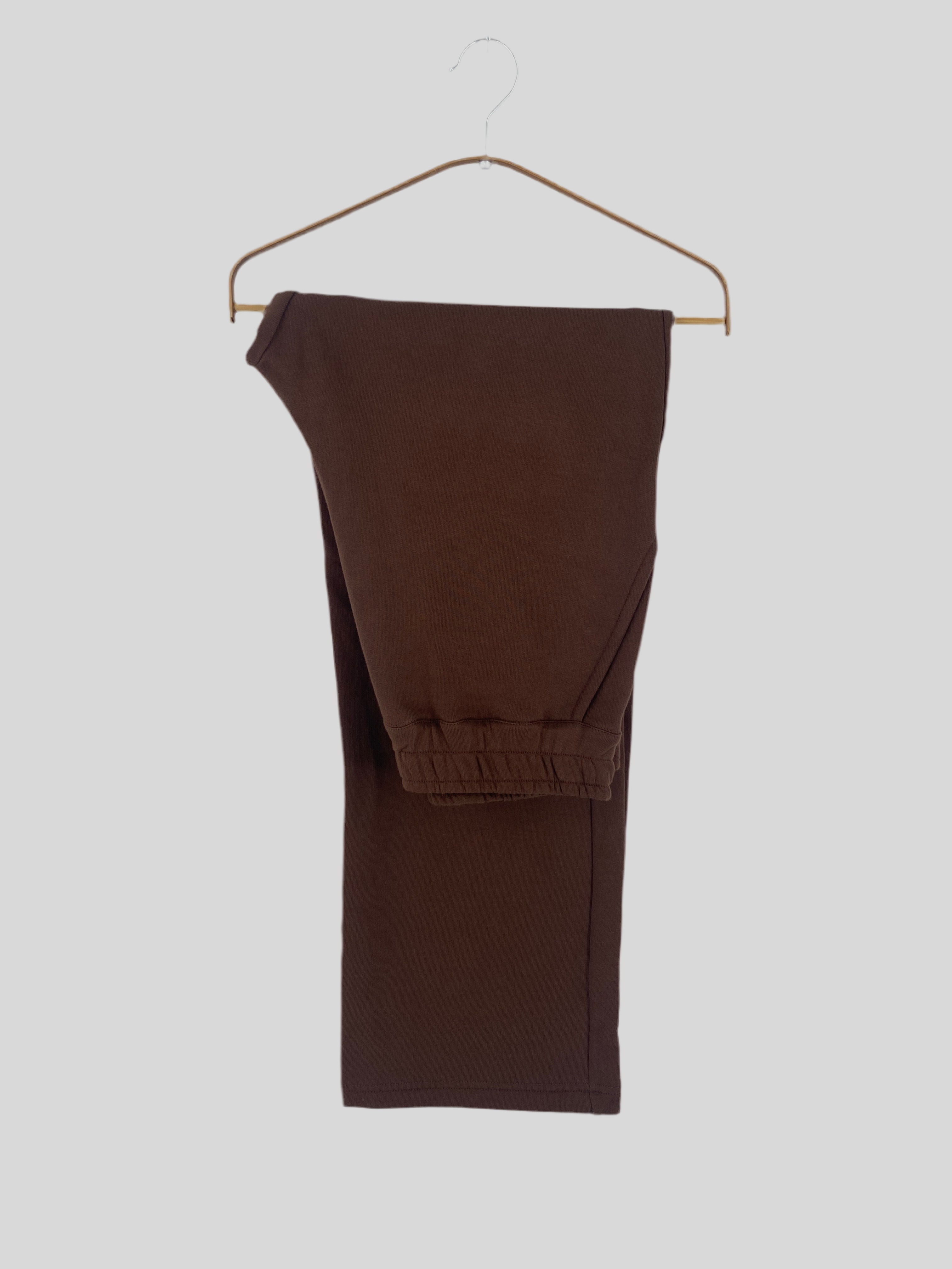 Eine Kopie der Frauen Palazzohose Bio-Sweat Schoko Gr L, gefaltet auf einem einfachen Drahtbügel, präsentiert sich vor einem schlichten Hintergrund.