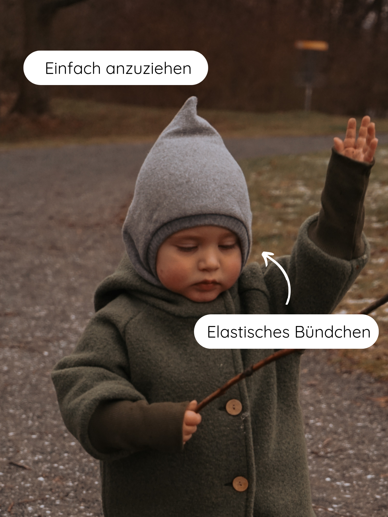 Kleinkind im Freien mit Schlupfmütze Strick - Maus: eine weiche, graue Strickmütze mit kleinem Peak, passend zur grünen Jacke mit Holzknöpfen. Betont: „Einfach anzuziehen“ und „Elastisches Bündchen“.