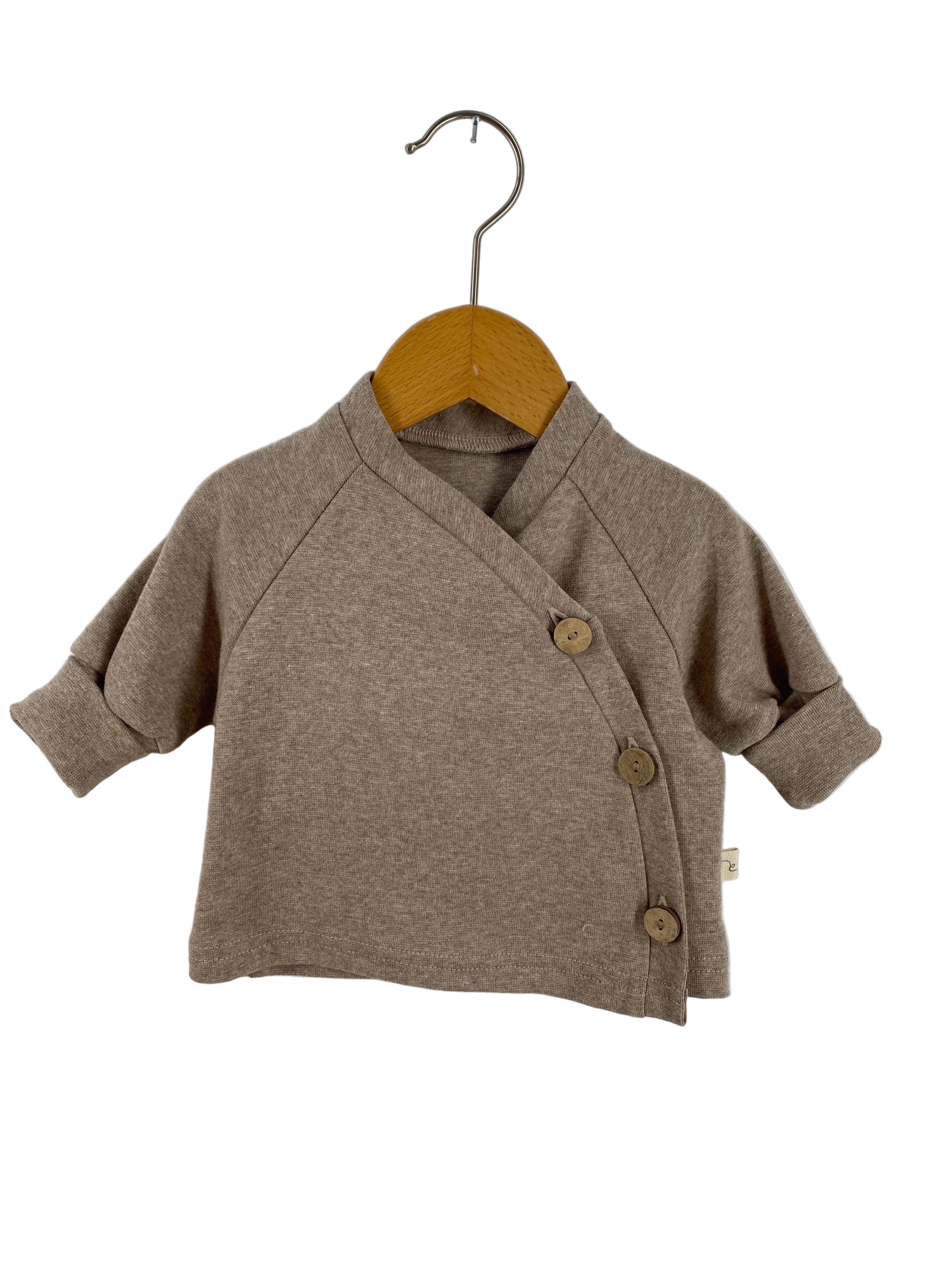 Babyschlüttli Feinstrick-Jersey Hafer meliert Gr 0M, ein langärmeliges Oberteil für Babys, mit asymmetrischer Knopfleiste und drei Holzknöpfen, aus leichtem Strickstoff, ideal als neutrales Kleidungsstück.