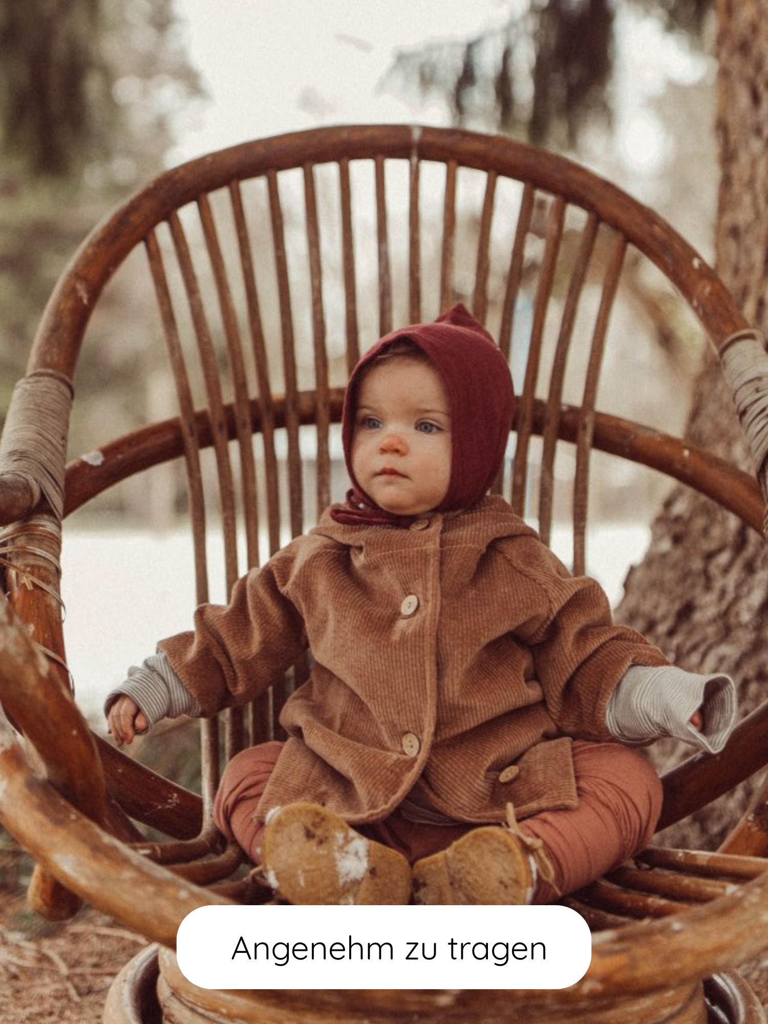 Kleinkind in Wichteljacke Breitcord Stretch - Weizen, sitzt in einem rustikalen Holzstuhl. Die Jacke zeigt große Holzknöpfe und eine niedliche Wichtelkapuze, ideal für Übergangswetter.