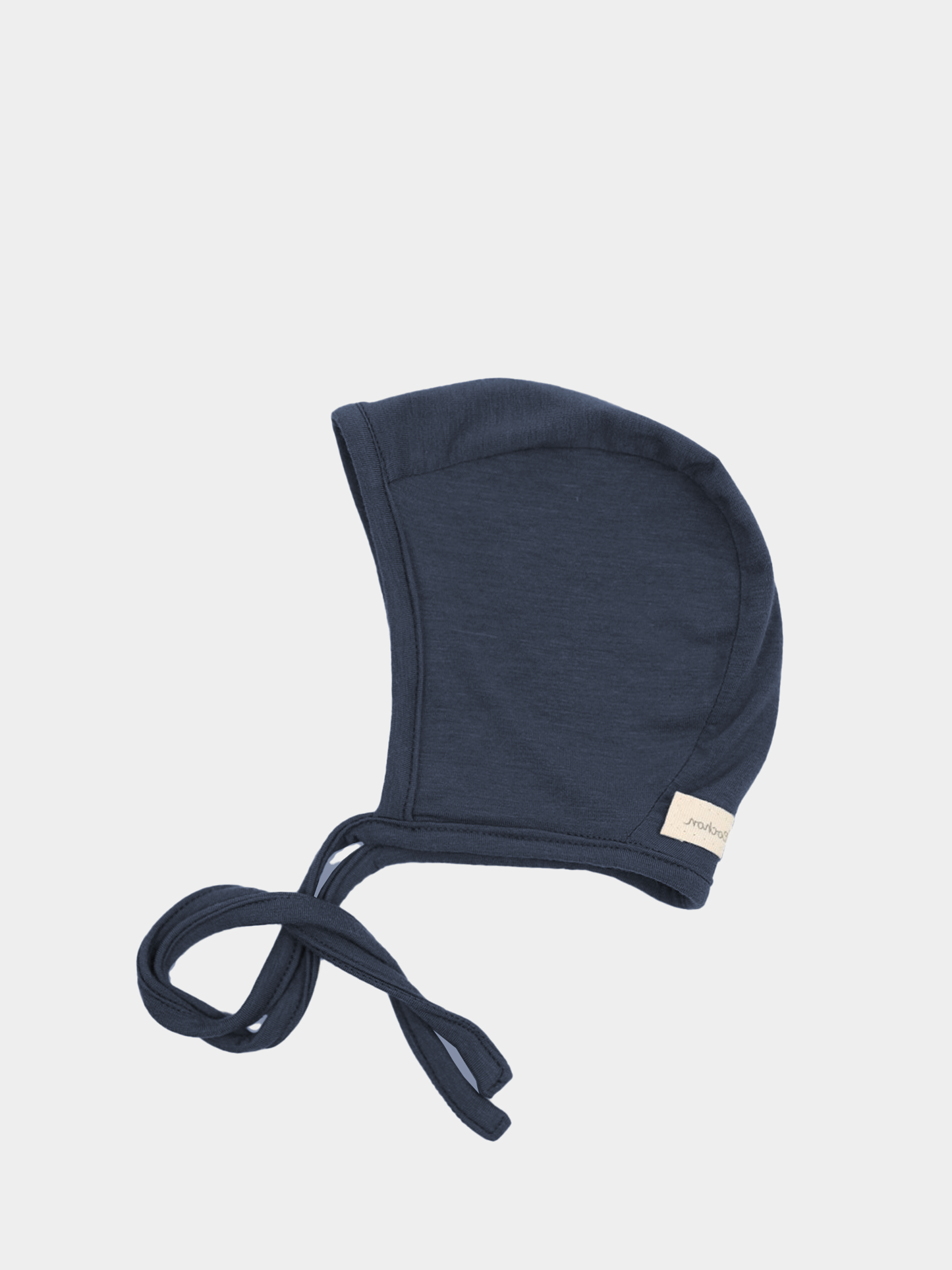 Babyhäubchen Kaschmir-Mix - Blaubeere: Ein weiches, navy-blaues Babyhäubchen mit langen Stoffbändern zum Binden, aus elastischem Micromodal-Kaschmirstoff, ideal für sanfte Wärme und Schutz, mit kleinem Seitenschild.