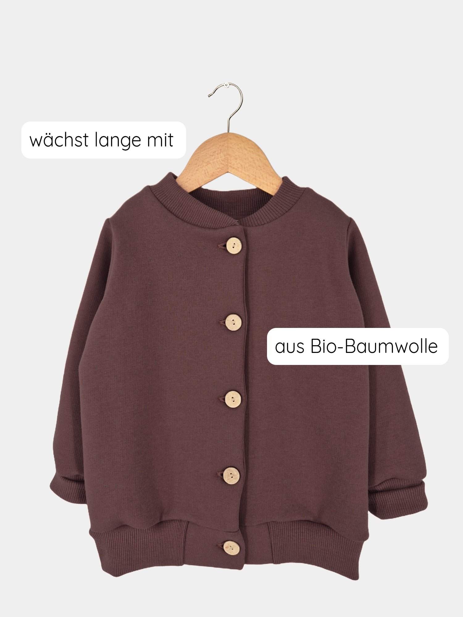 Bomberjacke Bio-Sweat - Schoko ab Gr 8/9Y auf Holzbügel; braune Kinderjacke mit Kokosknöpfen, gerippten Bündchen, aus Bio-Baumwolle, mit deutscher Textnote „wächst lange mit“.