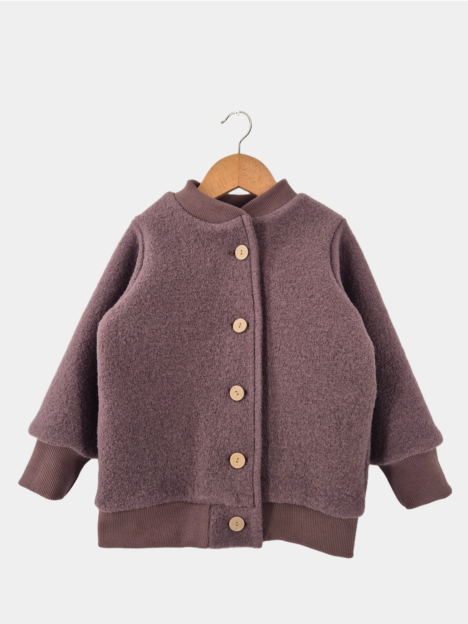 Bomberjacke Wollwalk - Malve, eine Kinderjacke aus Wollwalk mit Knöpfen, auf einem Bügel hängend, zeigt Details wie braune Strickärmel und Holzknöpfe.