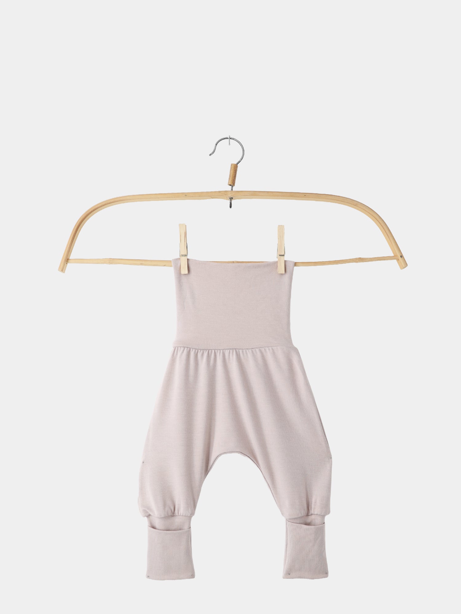 Babyknicker Bambusviskose Cremepuder: Ein weicher, locker geschnittener Babystrampler mit hohem Bund, aus atmungsaktiver Bambusviskose, auf einem Holzkleiderbügel hängend.