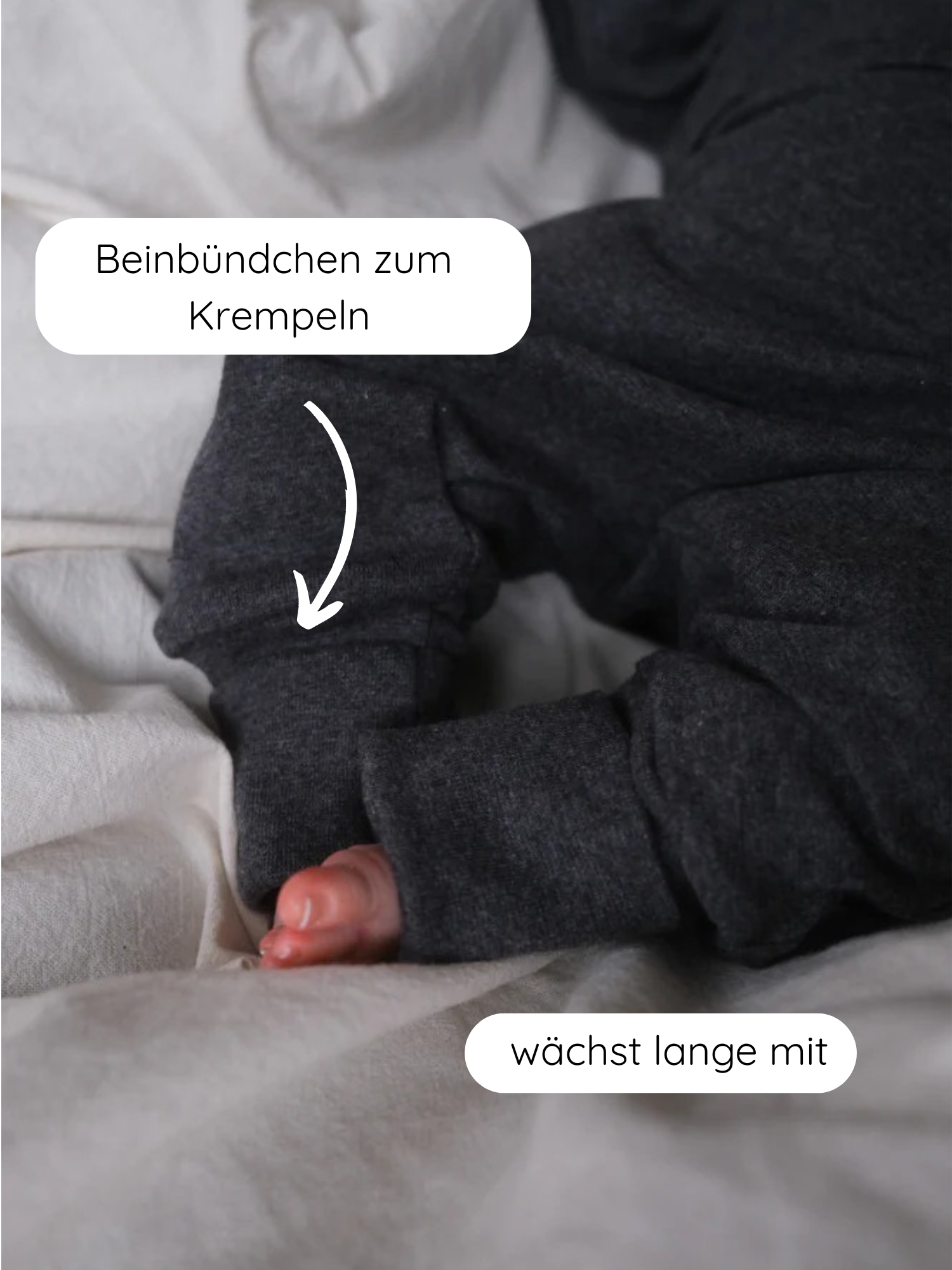 Babyknicker Feinstrick - Ruß Meliert: Nahaufnahme von Babybeinen in dunkelgrauer Jerseyhose mit langen Bündchen, die aufrollbar sind und mitwachsen, illustriert durch deutsche Textblasen.