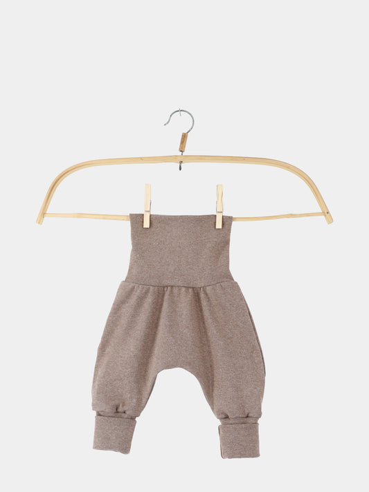 Babyknicker Feinstrick - Praline Meliert: Weiche, braune Babyhose aus elastischem Feinstrick-Jersey mit hohem Bund, tiefem Schnitt und schmalen Bündchen, aufgehängt an einem einfachen Holzbügel mit Metallhaken, vor weißem Hintergrund.