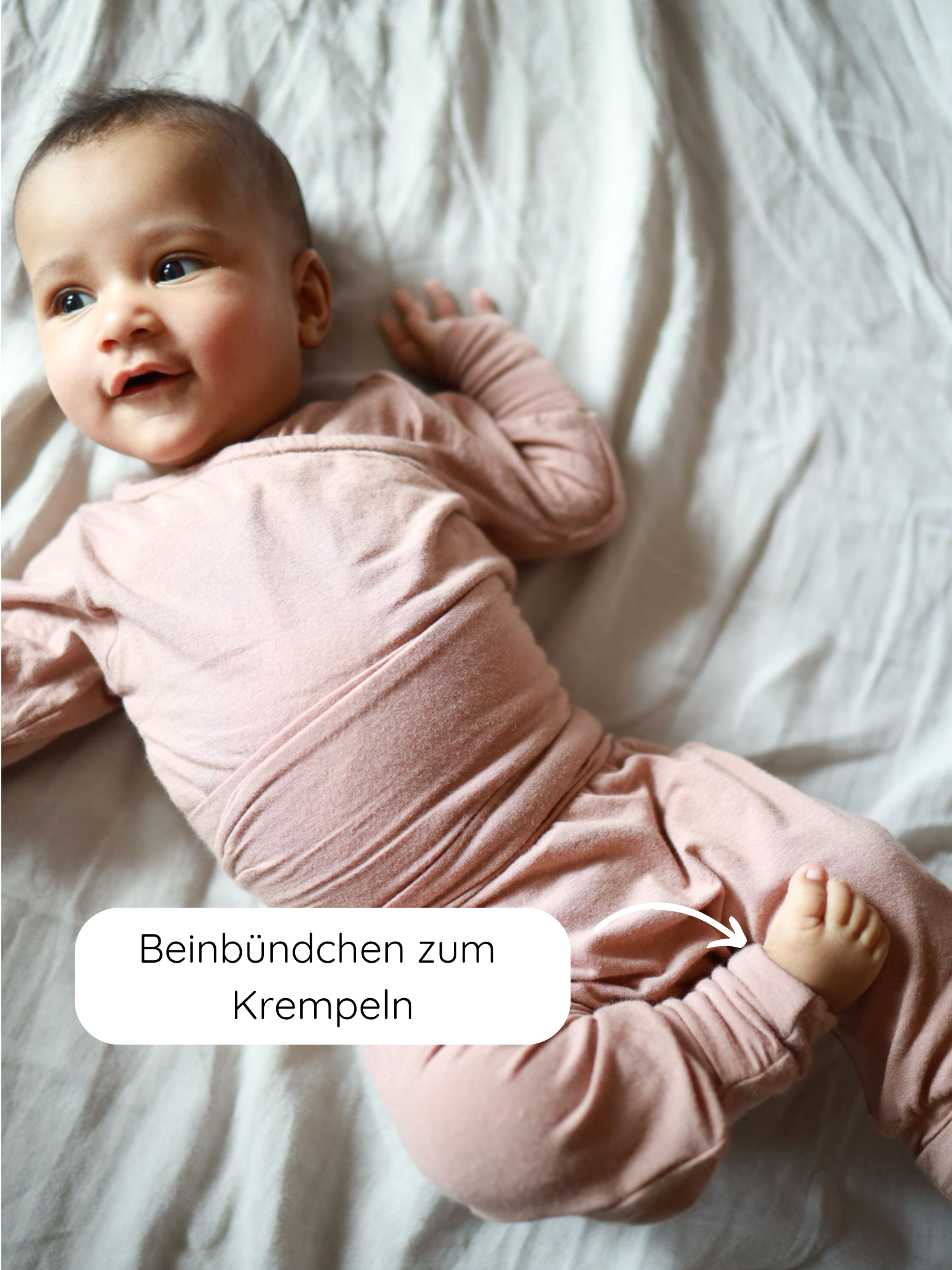 Baby in weichem, rosafarbenem Einteiler Babyknicker Kaschmir-Mix - Puder mit langen Ärmeln und umklappbaren Beinbündchen, die hervorgehoben sind, ideal für wachsende Babys und warme Füße.