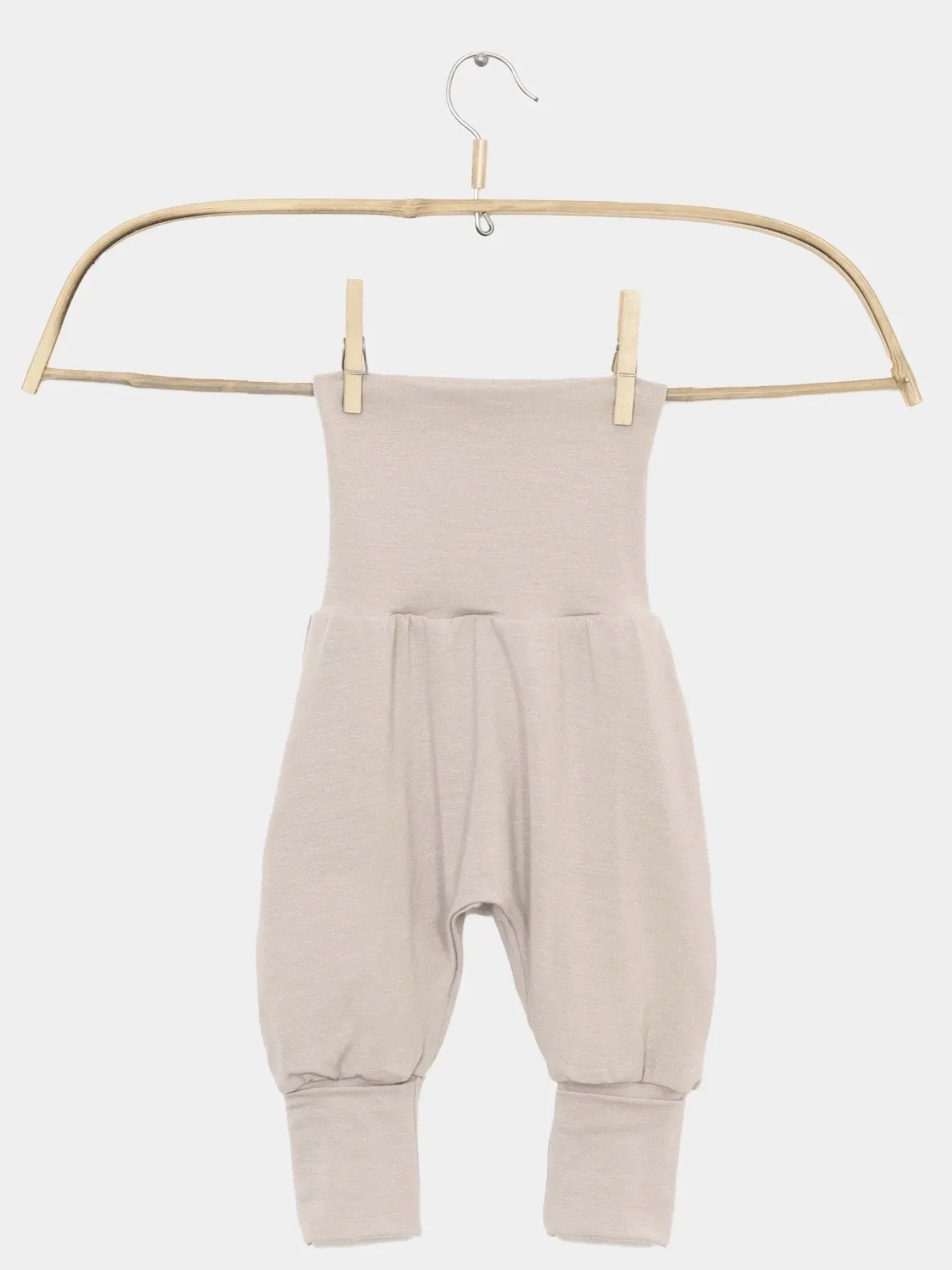 Babyknicker Kaschmir-Mix - Sand: Weiche, beige Baby-Haremshose mit hohem Klappbund, tiefem Schritt und Bündchen an den Knöcheln, hängt an einem schlichten Holzbügel.