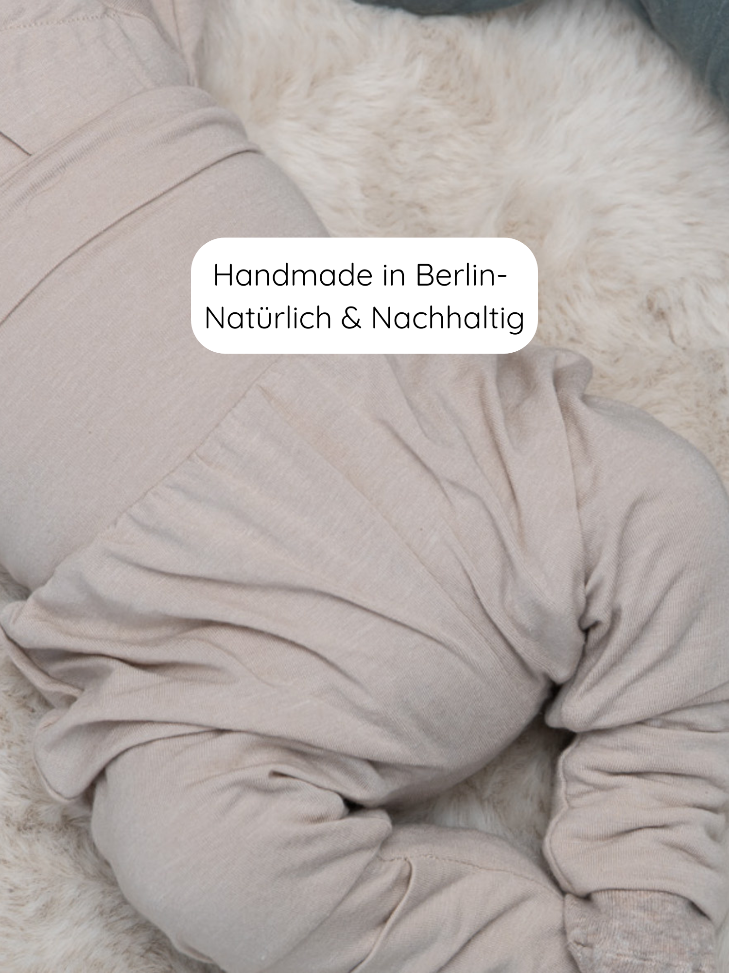 Babyknicker Kaschmir-Mix - Sand: Beige, handgemachte Babyhose aus Kaschmir-Mix mit praktischen Klappbündchen, liegt auf einem weichen, cremefarbenen Teppich. Text: Handmade in Berlin – Natürlich & Nachhaltig.