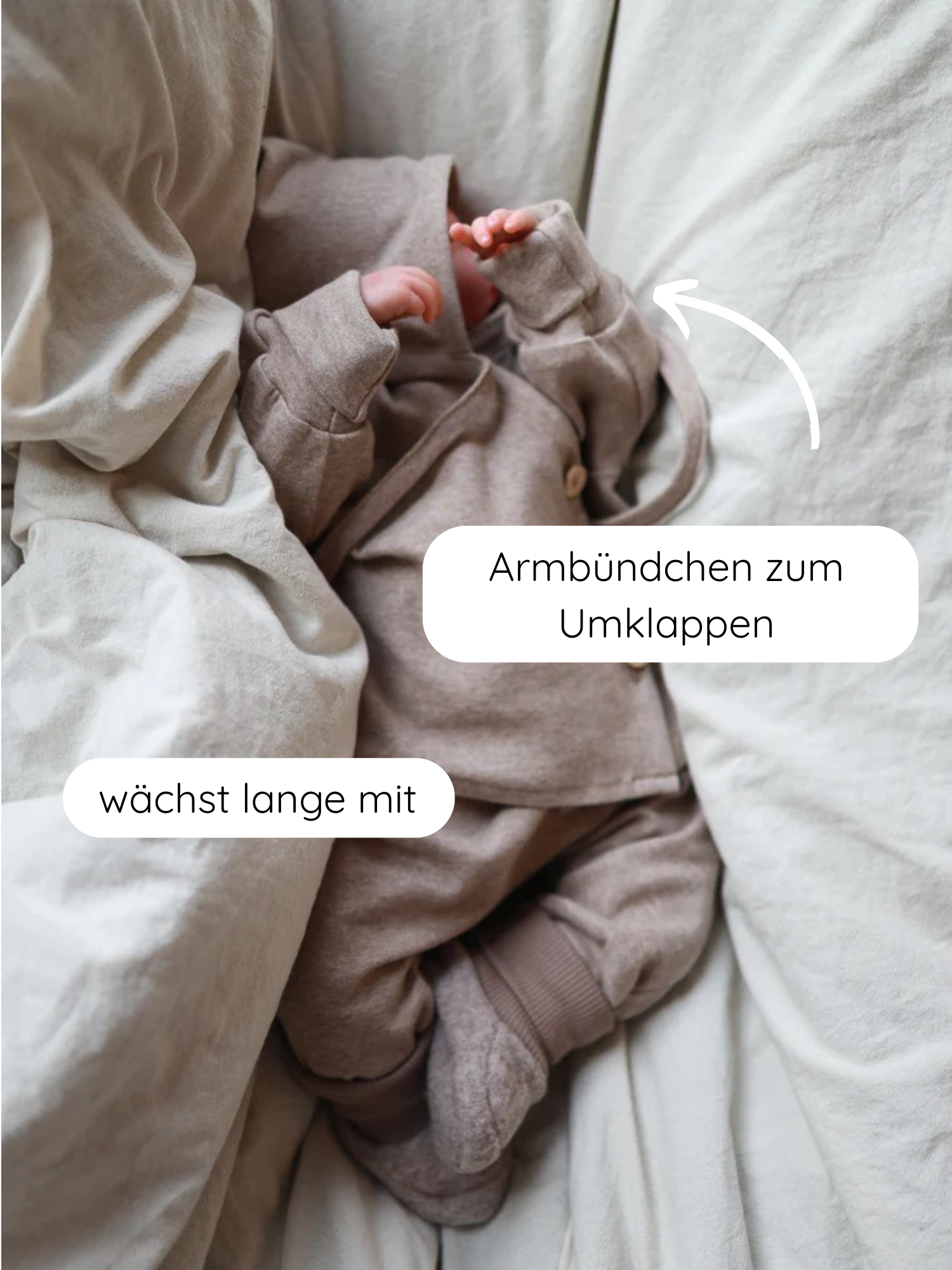 Baby in weichem Babyschlüttli Feinstrick - Hafer Meliert, mit umklappbaren Arm- und Beinbündchen, auf dem Bett liegend. Der Wickelverschluss erleichtert das Anziehen. Nachhaltig in Berlin gefertigt.