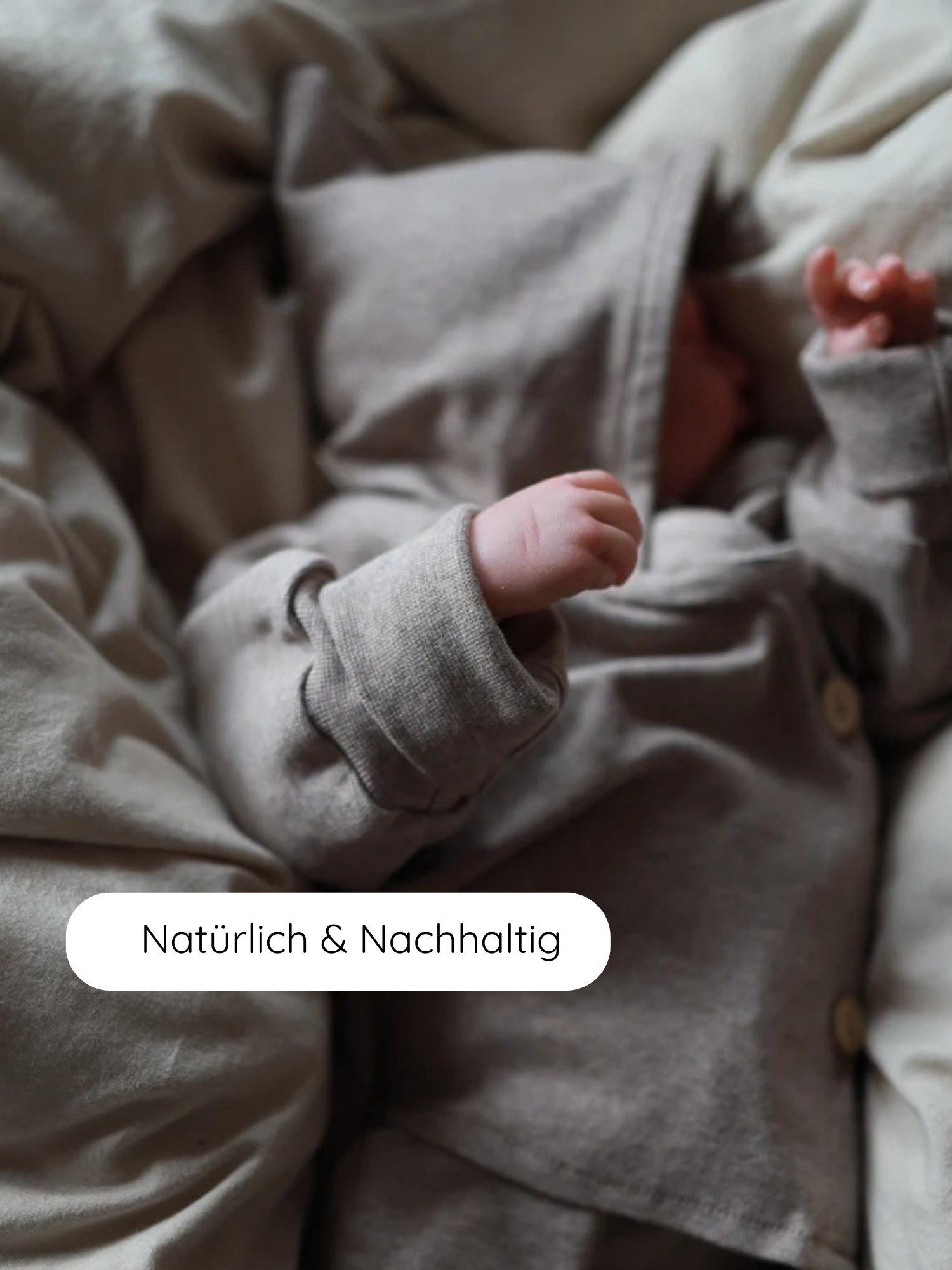 Neugeborenes in einem Baby-Schlüttli Feinstrick - Hafer Meliert, einem weichen, umweltfreundlichen Strick-Outfit mit Wickelverschluss, liegt auf neutralem Bettzeug. Text: Natürlich & Nachhaltig.