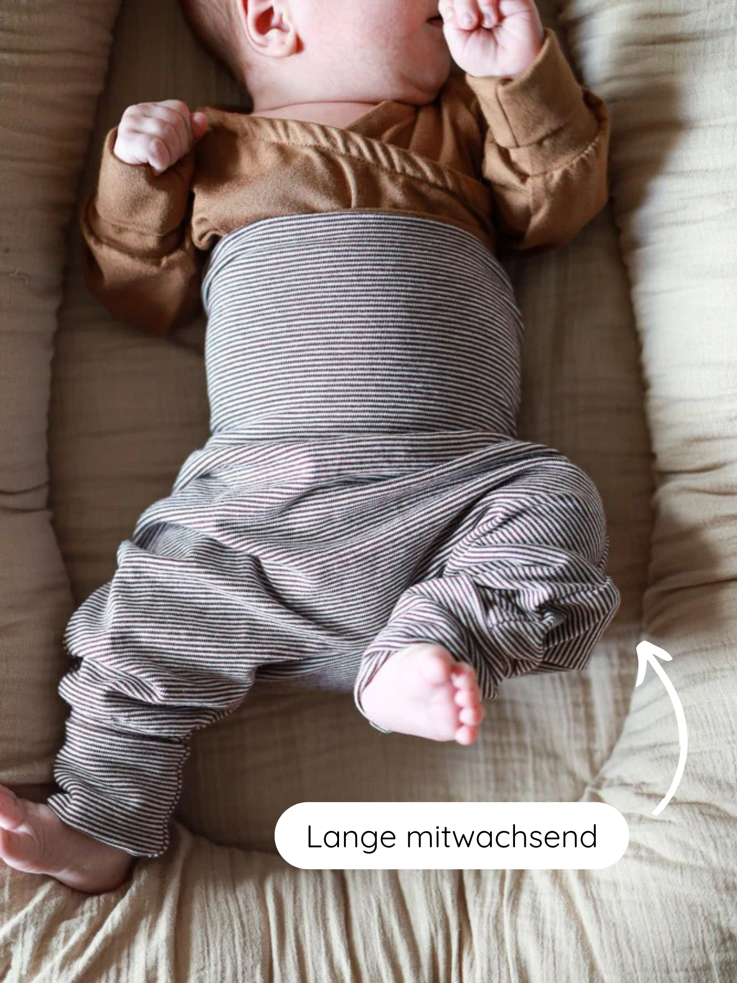 Baby liegt im Nest-Lounger, trägt Babyknicker Bio-Baumwolle - Schoko Ringel, braunes Langarmshirt, grauweiß gestreifte Hose; elastische Bündchen für Bewegungsfreiheit. Lange mitwachsend zeigt auf Seitenpanel.