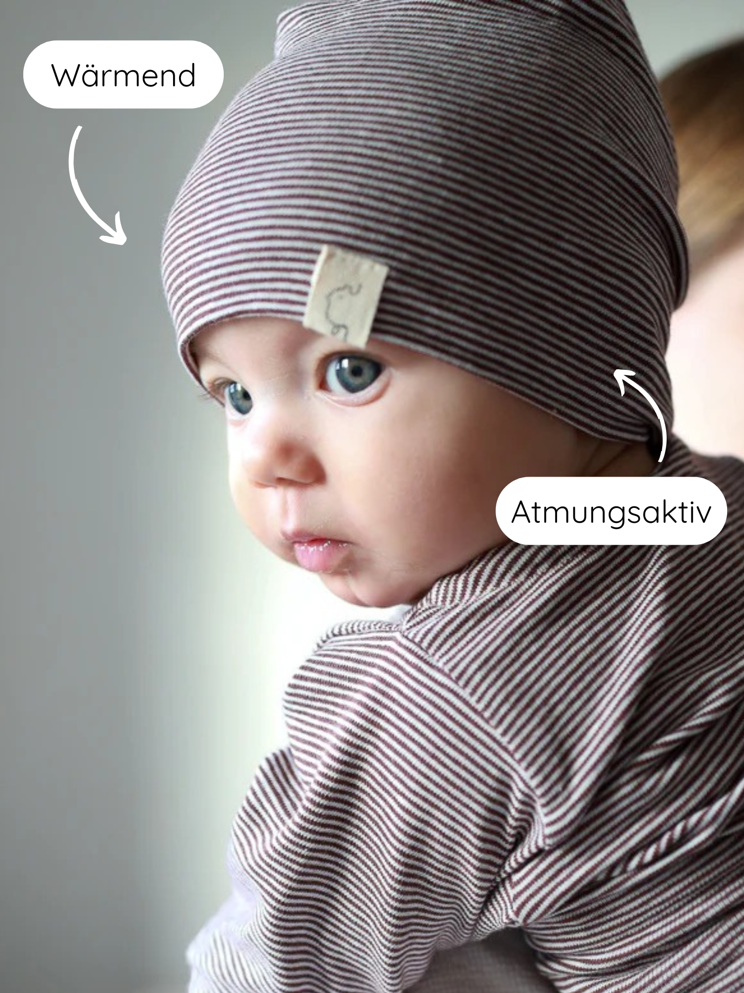 Kleines Baby seitlich, trägt Beanie Bio-Baumwolle - Ringel Schoko: braun-weiß gestreifte Mütze, atmungsaktives und wärmendes Material, ideal für jede Jahreszeit, fair in Berlin handgefertigt.