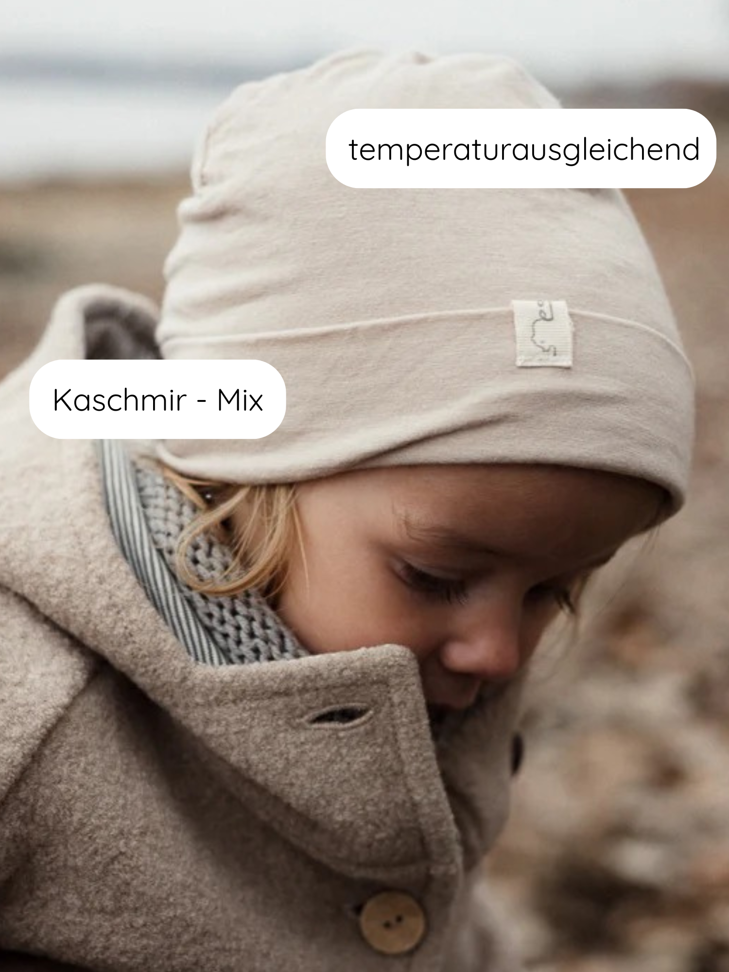 Kleinkind trägt die Beanie Kaschmir-Mix - Sand, eine beige-cream Mütze. Sie ist temperaturausgleichend, aus Kaschmir-Micromodal-Mix, und ideal für Neugeborene dank ihrer Weichheit und Atmungsaktivität.