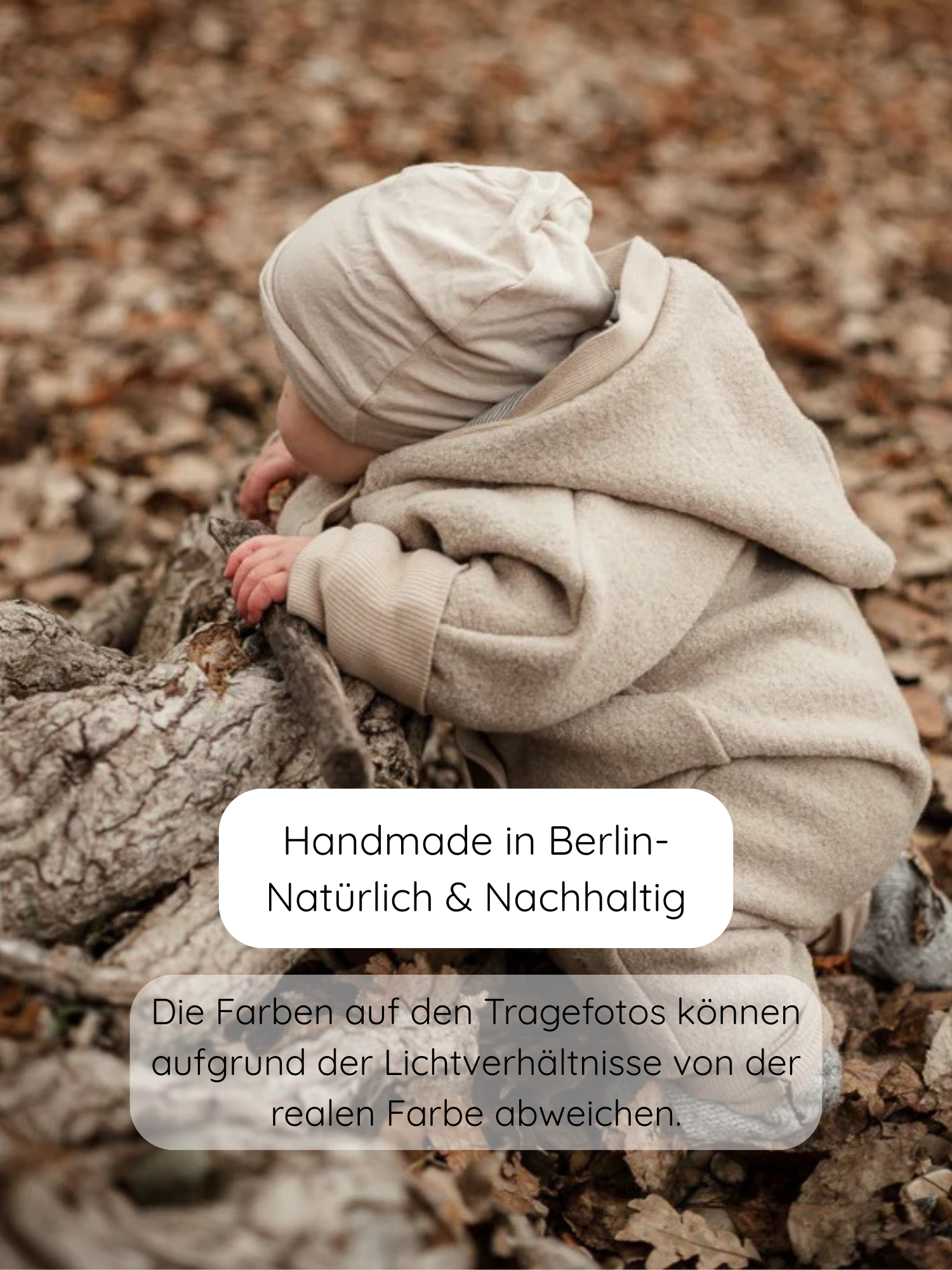 Kleinkind trägt eine Beanie Kaschmir-Mix - Sand, lehnt auf einem Baumstamm im Wald. Die weiche, dehnbare Mütze passt sich perfekt an, ideal für Babys.