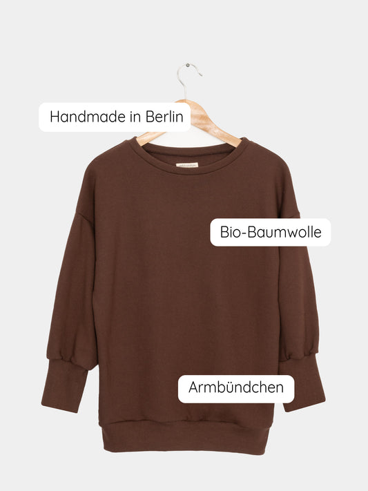 Frauen Pumppulli aus Bio-Baumwolle - Schoko auf einem Kleiderbügel, zeigt einen lässigen, zeitlosen Stil mit lockerem Schnitt und überschnittenen Schultern für maximalen Komfort.