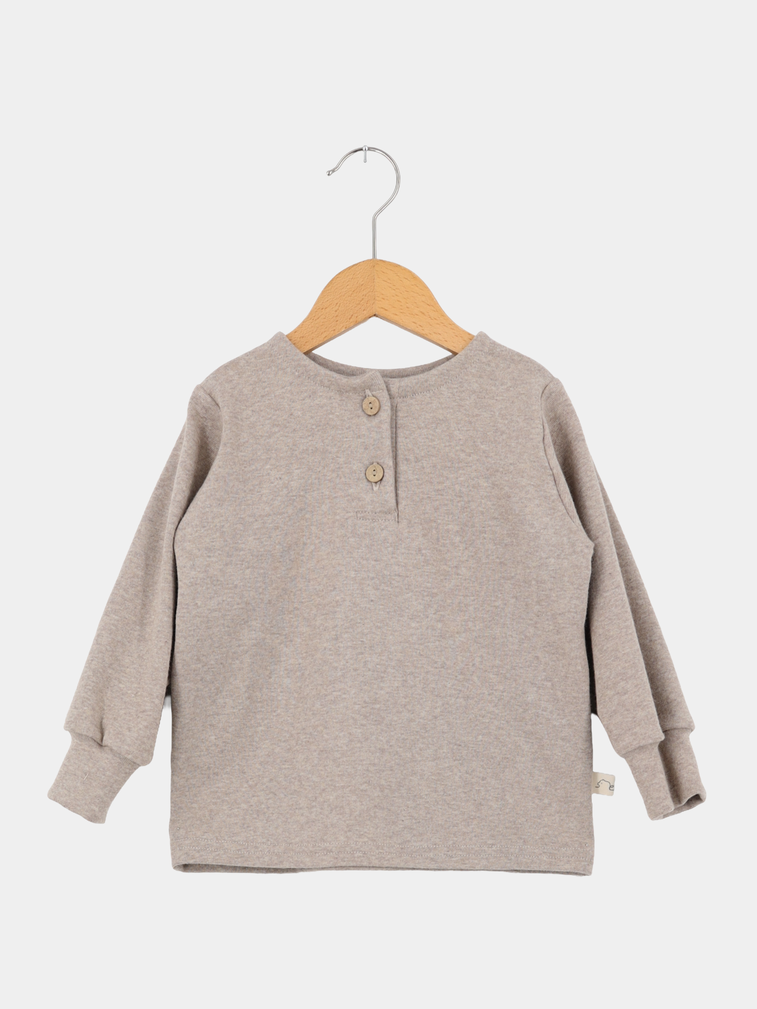 Hemdchen Feinstrick - Hafer: Langärmeliges, heather-beiges Pullover-Shirt aus elastischem Feinstrick mit Rundhalsausschnitt, zweiknöpfiger Knopfleiste und gerippten Bündchen, auf einem Holzkleiderbügel hängend.