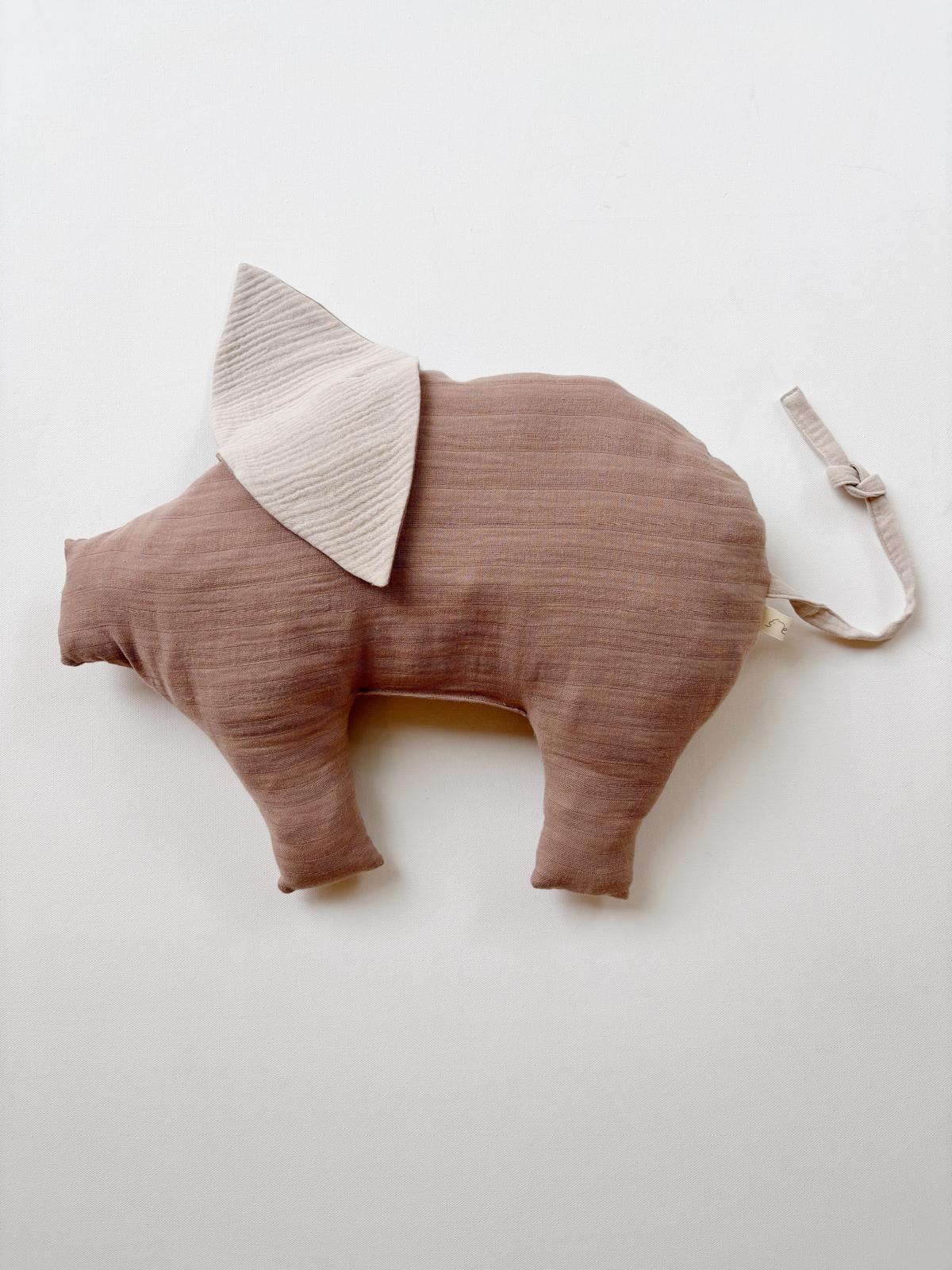 Teddy-Schwein Bio-Musselin - Puder: Weiches, schweineförmiges Kissen aus braunem Musselin-Stoff mit vier Beinen, einer Schnauze, einem beigen Ohr und einer Stoffschlaufe, ideal zum Kuscheln und Liebhaben.