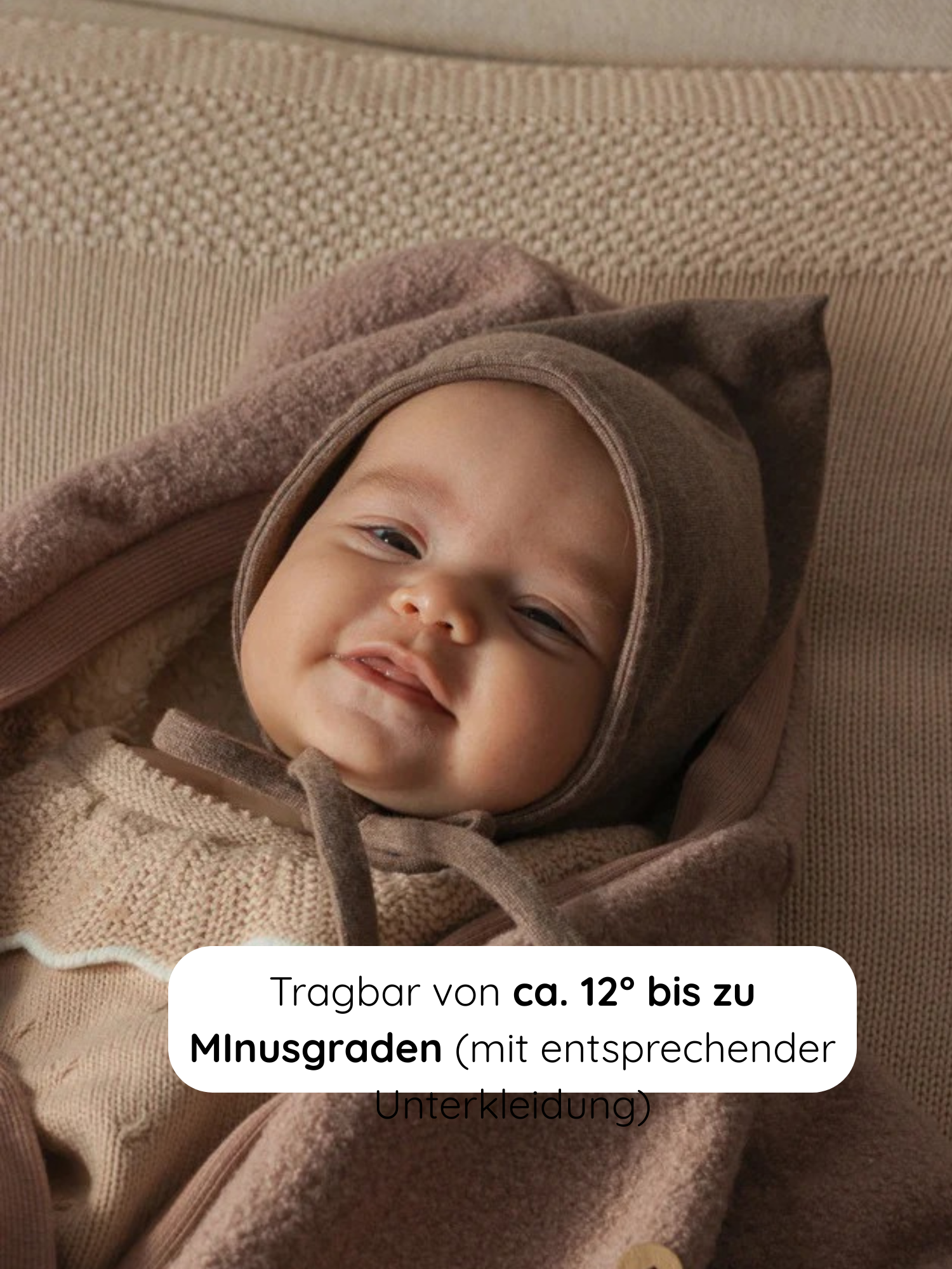Ein lächelndes Baby liegt in einem Winter Wollwalk Overall mit Teddyfutter - Puder, auf einer strukturierten, beigen Strickunterlage. Der Overall ist für Temperaturen von 12°C bis Minusgrade geeignet.