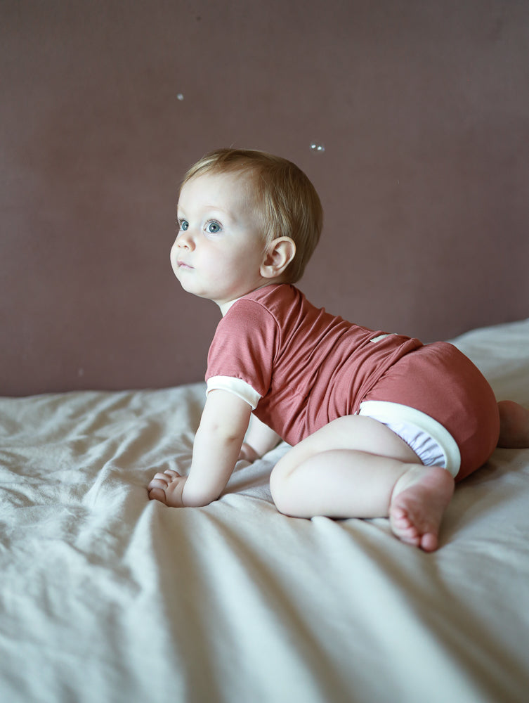 Kurzarm Loopbody Bambusviskose - Pfirsich: Ein weicher, elastischer Babybody ohne Knöpfe, mit kurzem Arm und einzigartigem Loop-Design, das den Bauch sanft umschließt und für einfaches An- und Ausziehen sorgt.