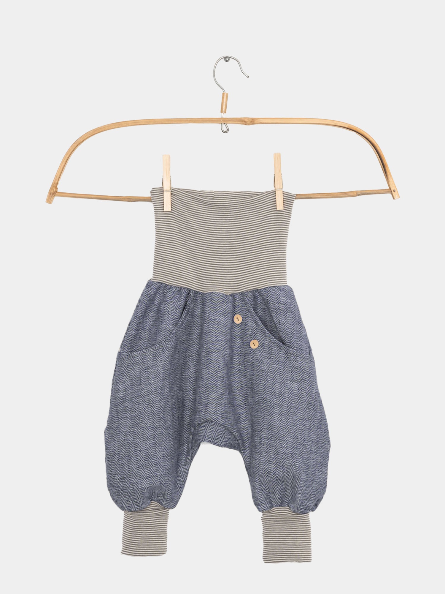 Knickerbocker Fischgrat Blaubeere: Ein Kinder-Jumpsuit mit grau-weiß gestreiftem Oberteil und blauem Chambray-Harem-Hosenstil, Seiten mit Taschen und Holzknöpfen, gestreifte Bündchen an den Knöcheln.
