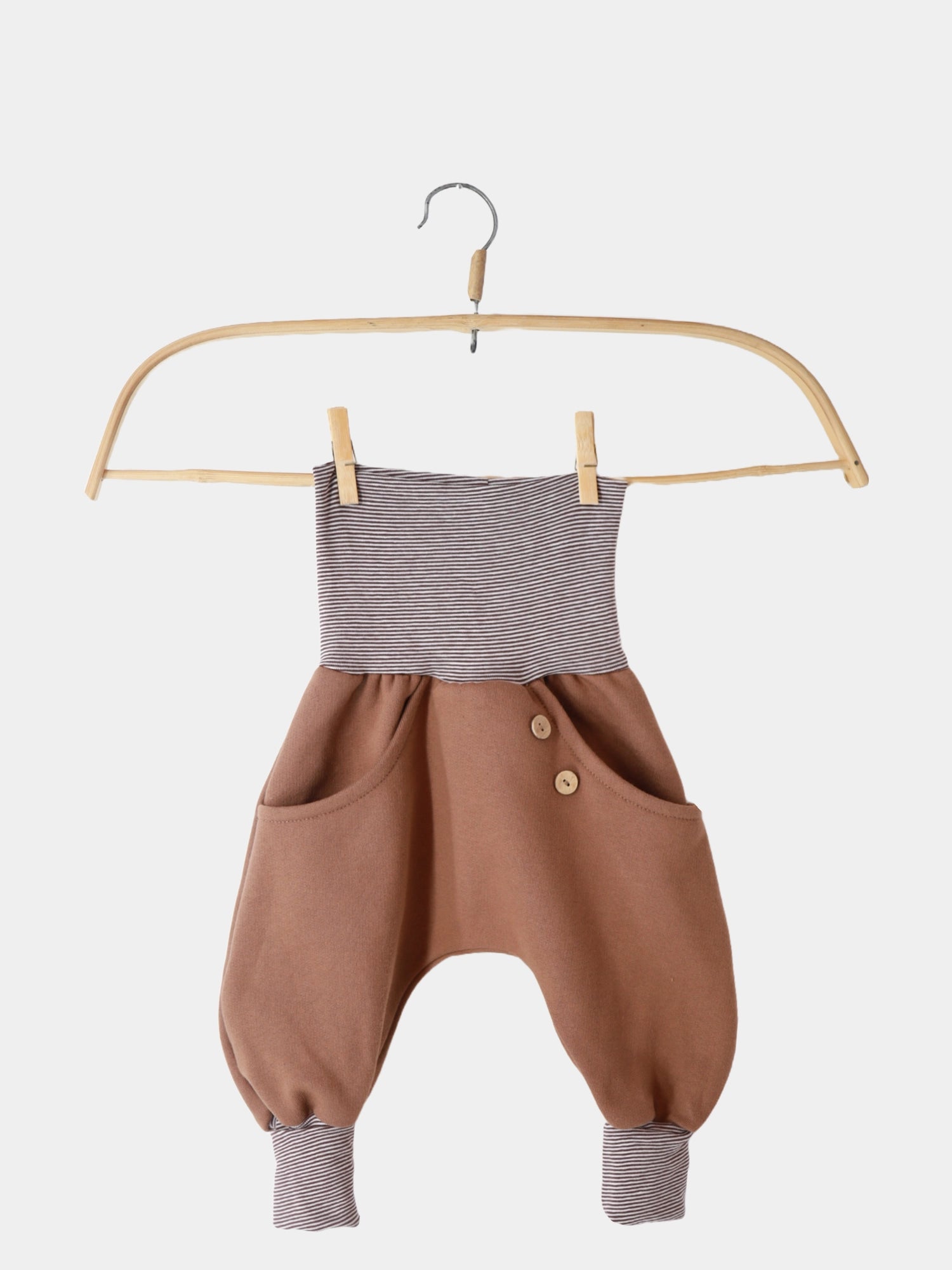 Knickerbocker Bio-Sweat mit Ringelbündchen - Nougat, lässig auf einem Kleiderbügel präsentiert. Sichtbar sind die durchgehende Kängurutasche und die umklappbaren Bündchen, die für zusätzliche Bewegungsfreiheit sorgen.