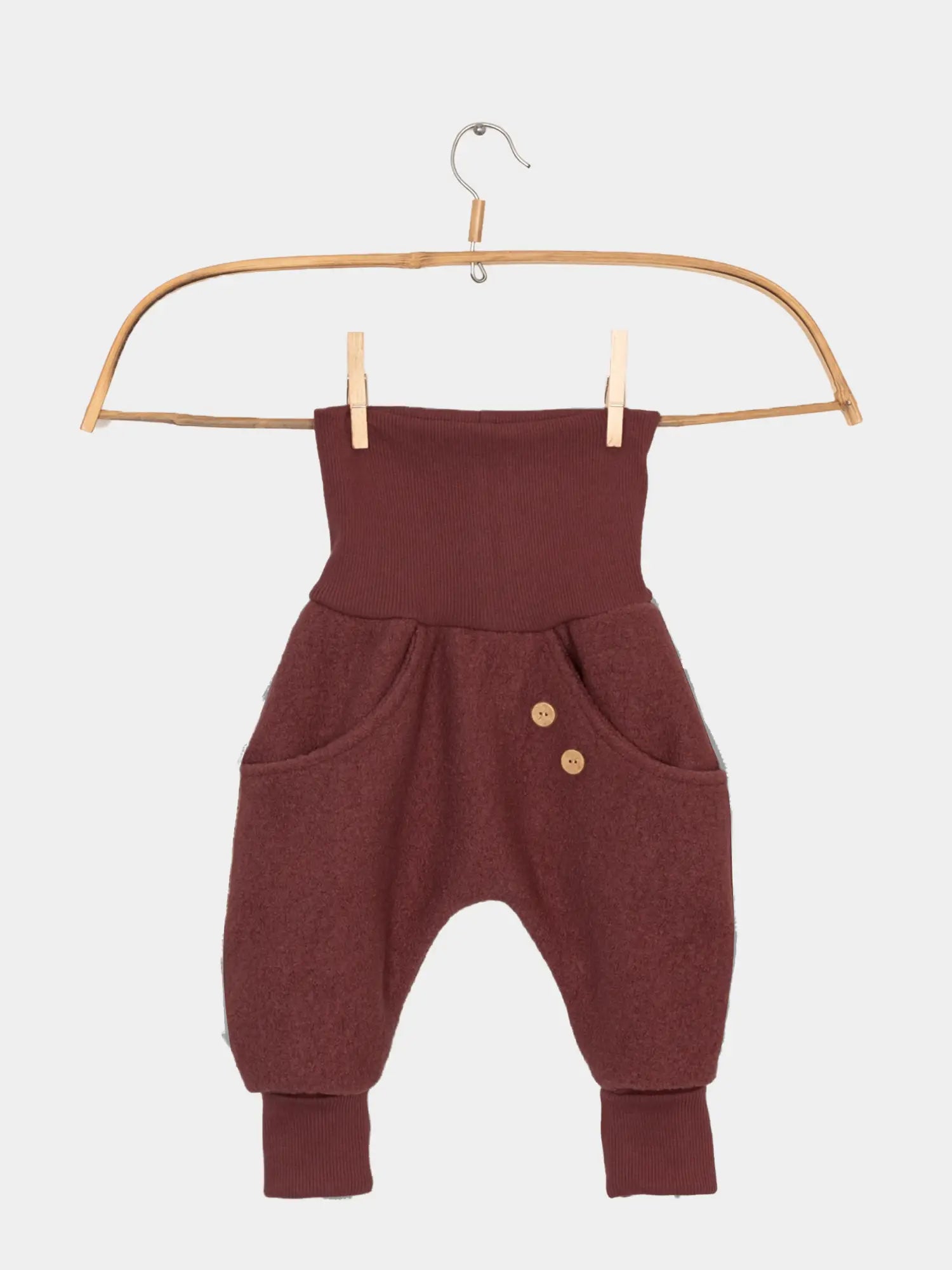 Knickerbocker Wollwalk - Ziegel: Kinderhose in Burgunder mit breitem, geripptem Bund und Knöchelbündchen, verziert mit zwei Holzknöpfen, präsentiert an einem Bambuskleiderbügel vor weißem Hintergrund.