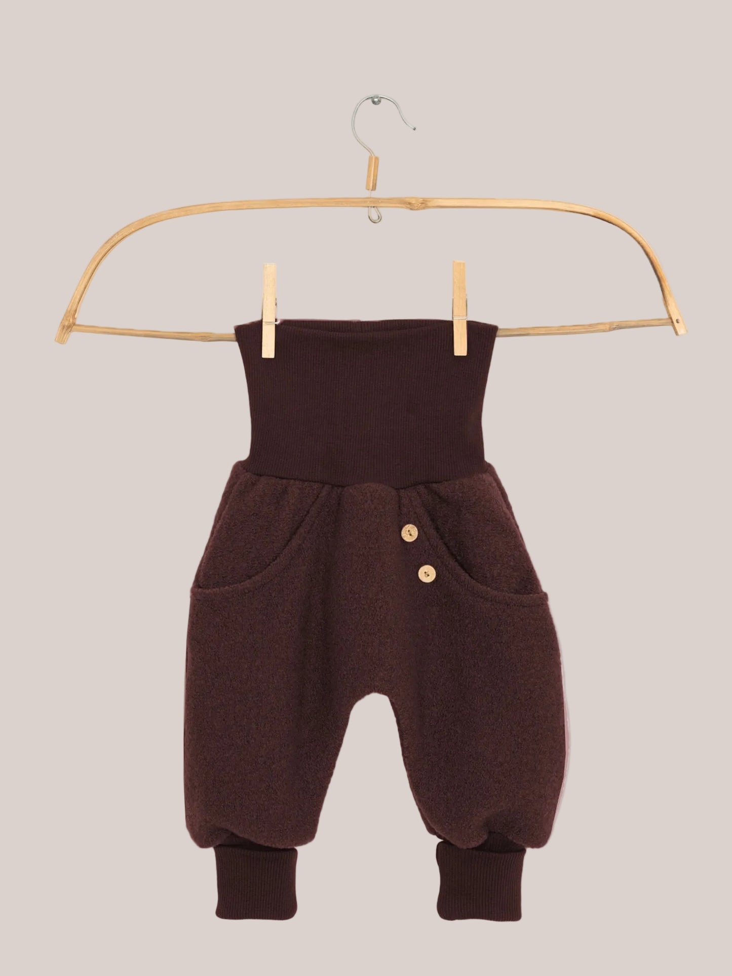 Knickerbocker Wollwalk - Schoko: Kleine haremartige Hose mit hohem, geripptem Bund, Seitentaschen mit Holzknöpfen, flauschigem Wollstoff, und gerippten Knöchelbündchen, hängt an einem Holzkleiderbügel.