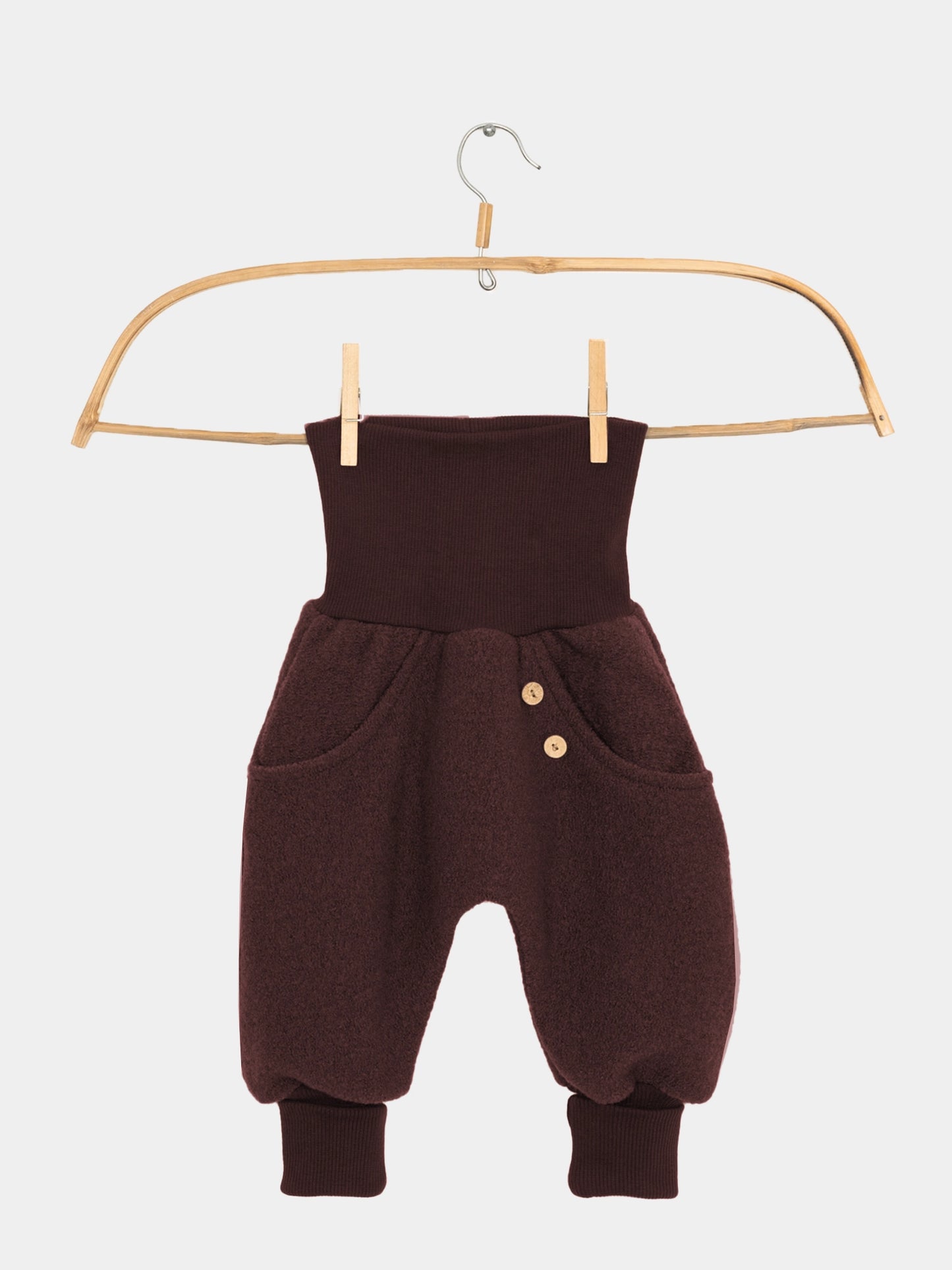 Knickerbocker Wollwalk - Schoko: Kleine haremartige Hose mit hohem, geripptem Bund, Seitentaschen mit Holzknöpfen, flauschigem Wollstoff, und gerippten Knöchelbündchen, hängt an einem Holzkleiderbügel.