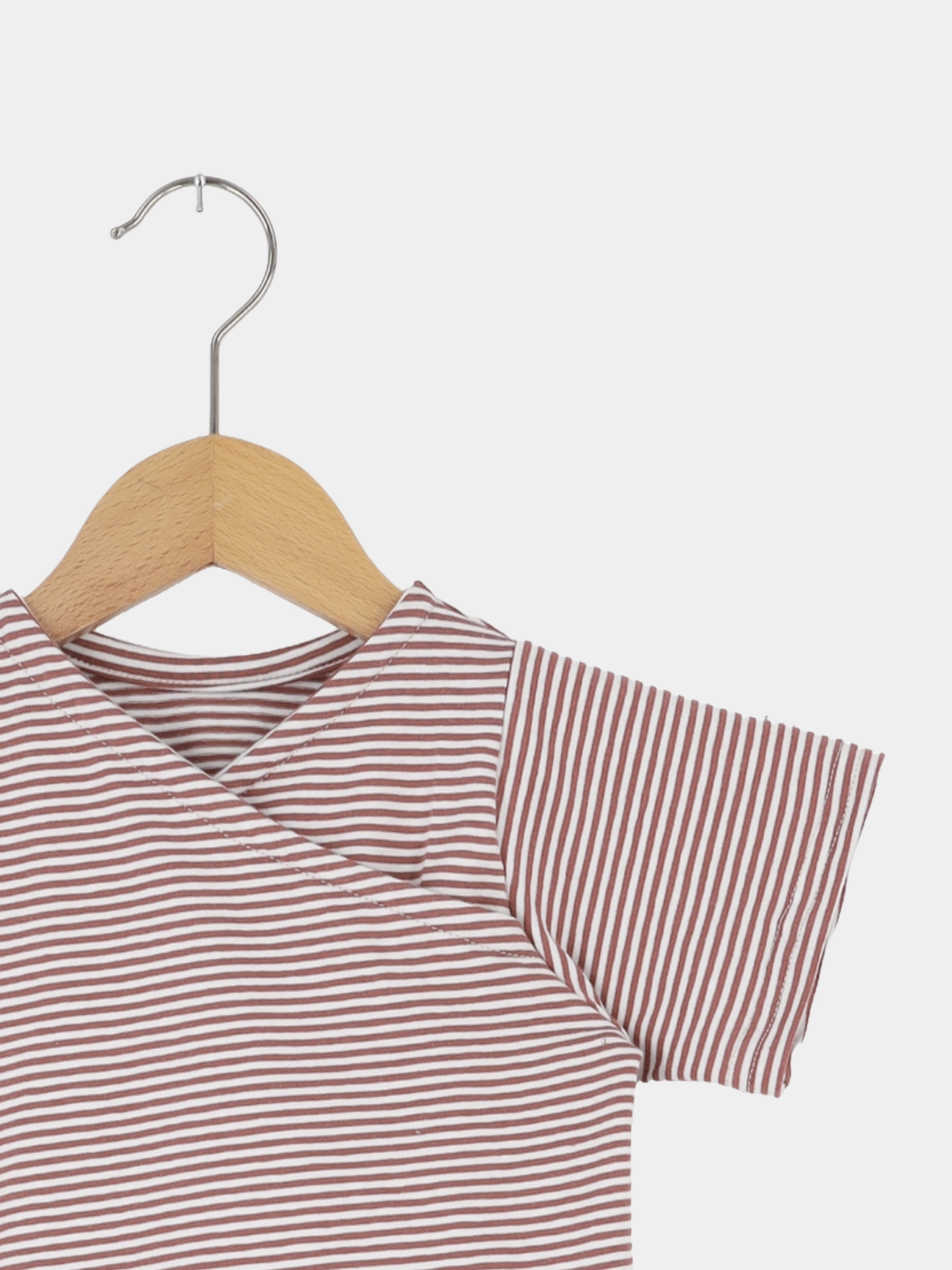 Kurzes Wickelshirt Baumwolle - Ringel Ziegel: Ein kurzärmeliges Wickelshirt auf einem Holzbügel, mit feinen weißen und rostbraunen Streifen, aus weicher, atmungsaktiver Ökotex-zertifizierter Baumwolle, handgefertigt in Berlin.