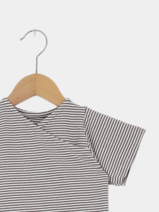 Kurzes Wickelshirt Baumwolle - Ringel Praline: Ein kurzärmeliges, grau-weiß gestreiftes Kinderoberteil auf einem Holz-Metall-Bügel, handgefertigt in Berlin, weich, bequem und aus elastischer, atmungsaktiver Ökotex-zertifizierter Baumwolle.
