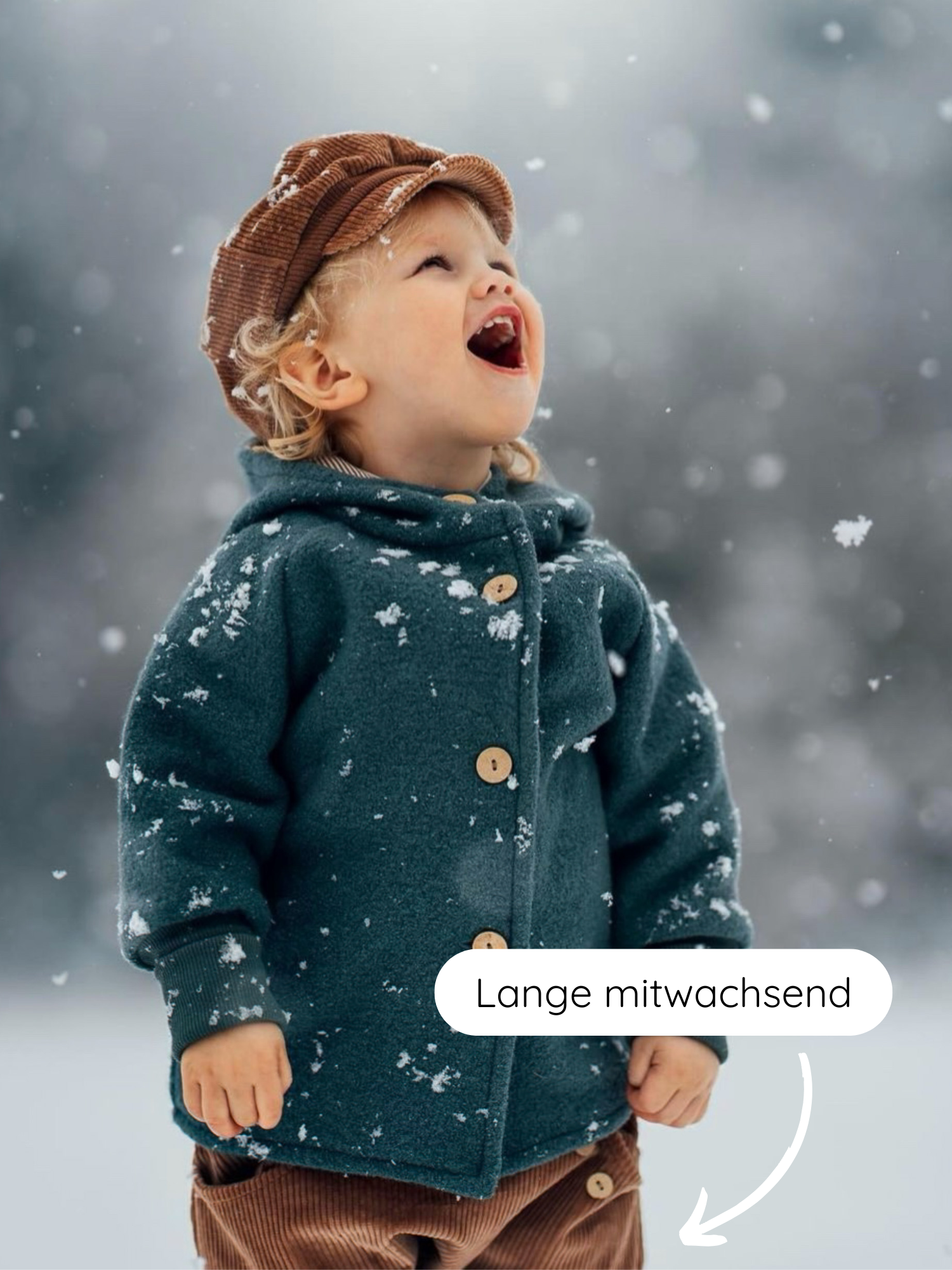 Kleinkind im Schnee trägt Knickerbocker Breitcord Stretch - Weizen, braune Cordhose mit mitwachsendem Bund, passend für kühle Tage. Kind schaut nach oben, um Schneeflocken zu fangen.