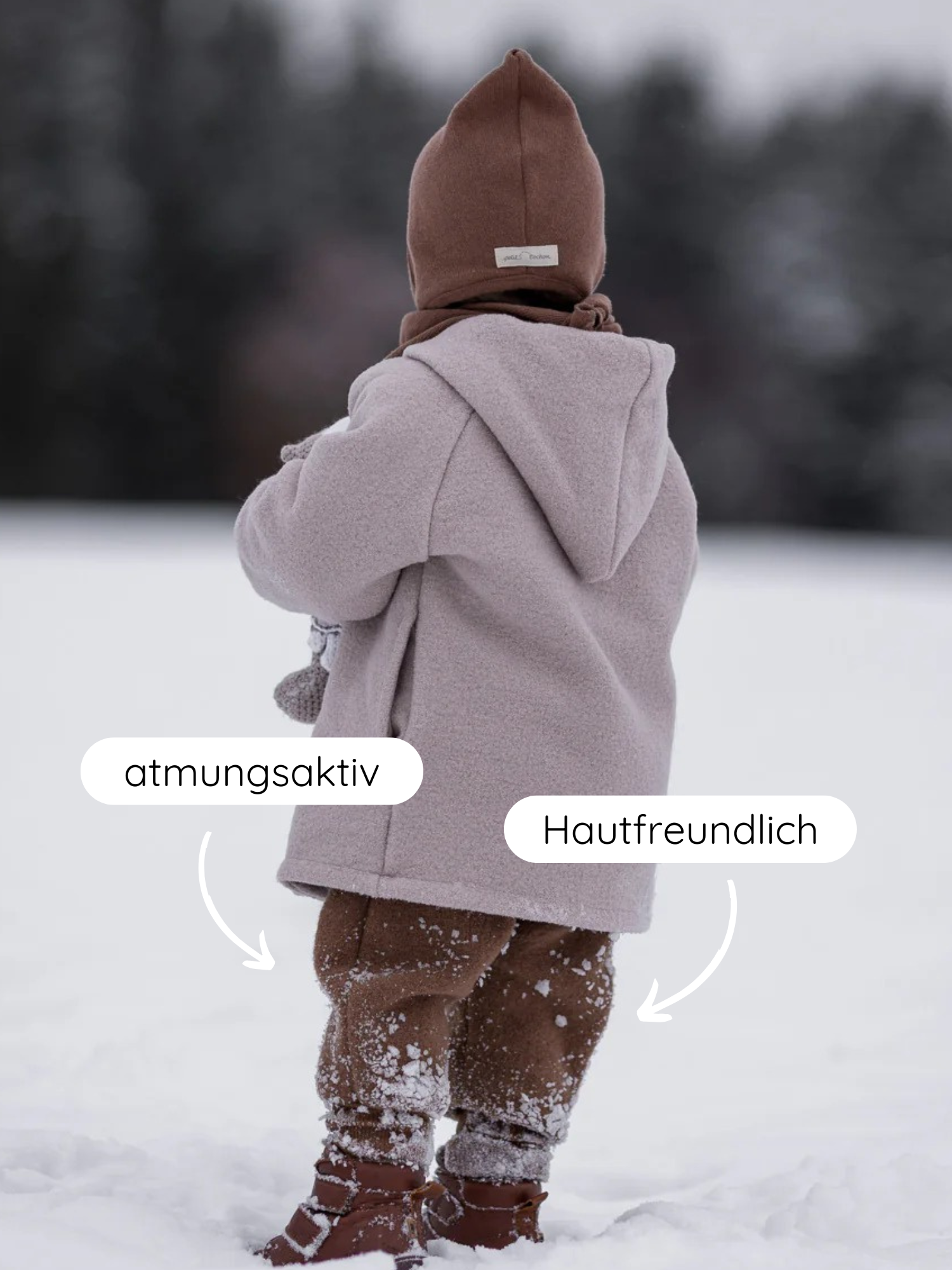 Ein Kind steht im Schnee, trägt Knickerbocker Wollwalk - Schoko. Die atmungsaktive, hautfreundliche Hose bietet Komfort und Bewegungsfreiheit, ideal für kalte Wetterbedingungen.
