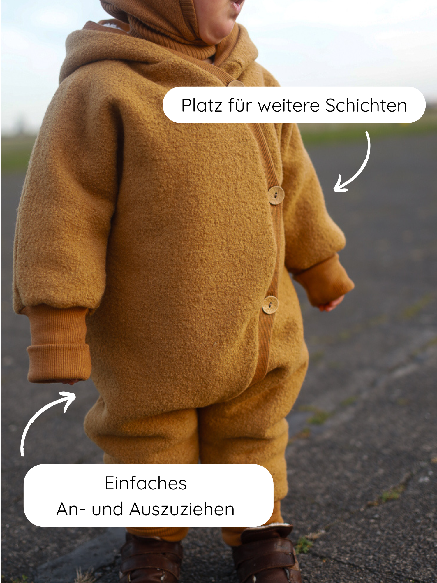 Kleinkind im Freien trägt den Kuschelanzug Wollwalk - Honig aus 100% Schurwolle mit Baumwollfutter, Holzknöpfen, gerippten Bündchen, großzügigem Schnitt für Bewegungsfreiheit und einfachem An- und Ausziehen.