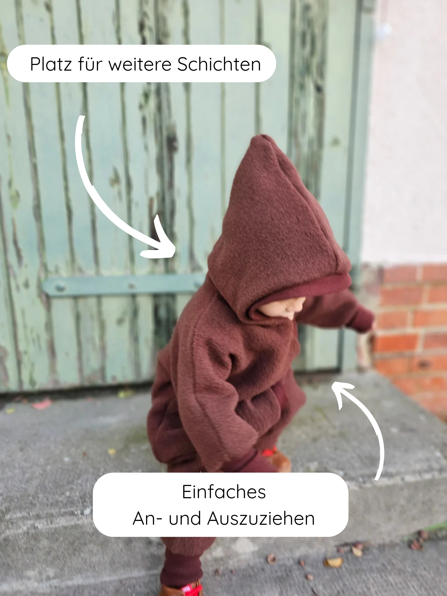 Kleinkind im „Kuschelanzug Wollwalk - Schoko“ auf einer Türstufe. Der Anzug aus 100% Schurwolle hat Platz für Schichten, ist leicht anzuziehen und bietet Bewegungsfreiheit.