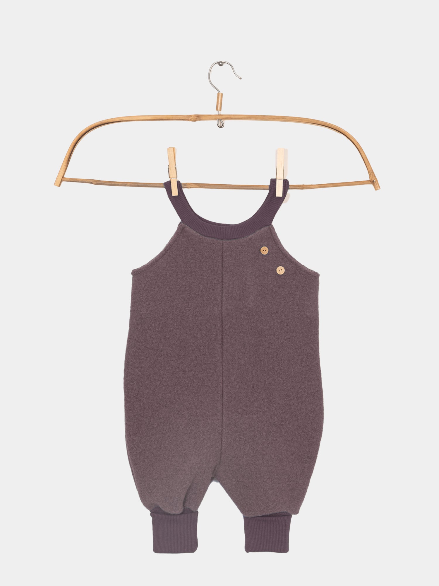 Schlupflatzhose Wollwalk - Malve von PETIT COCHON, ein Baby-Romper aus 100% Schurwolle, dargestellt auf einem Bügel ideal für kalte Jahreszeiten. Schneehose und Matschhose.