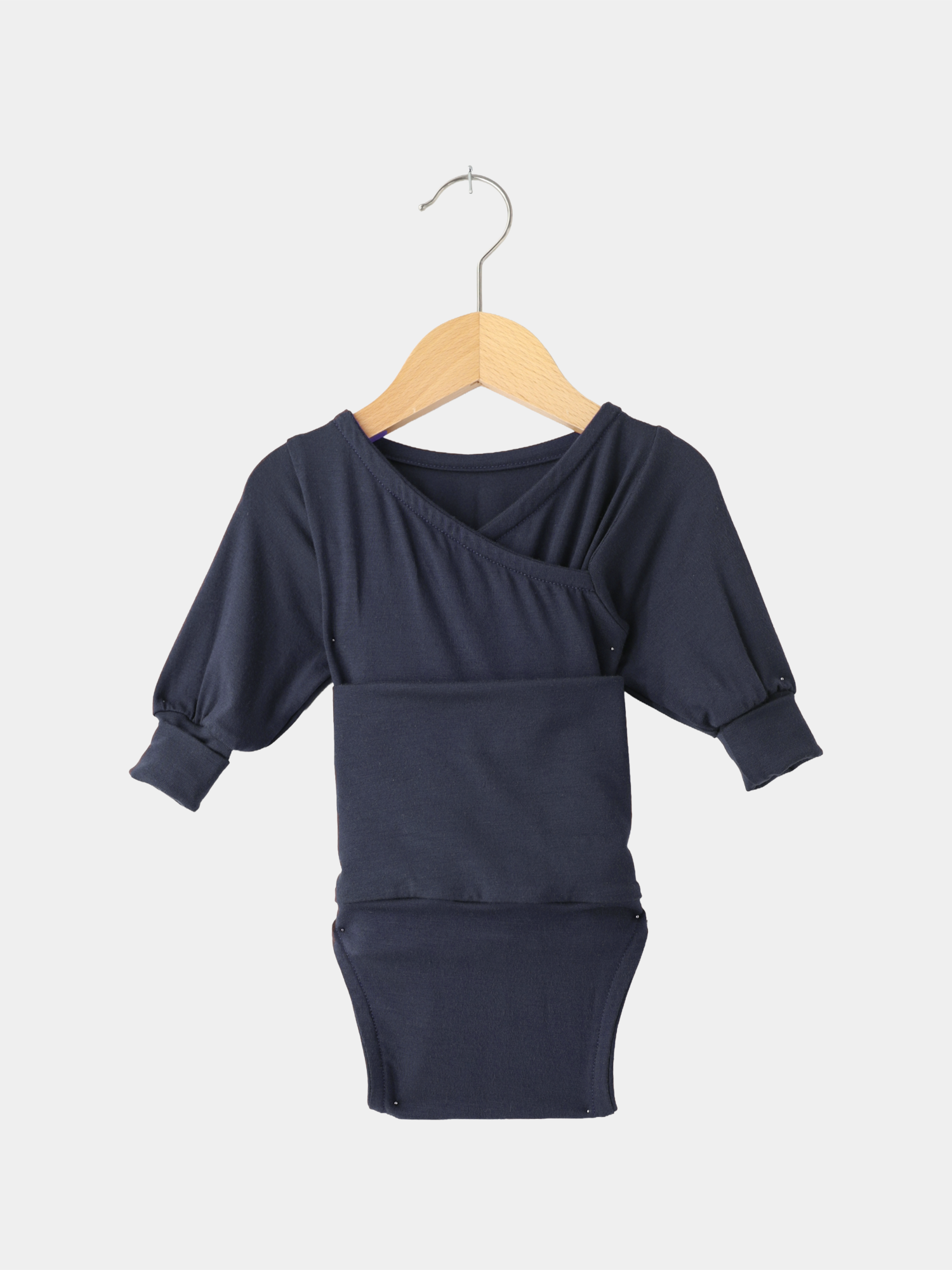 Loopbody Bambusviskose - Nachtblau: Navy-blauer, langärmeliger Babybody mit Wickelkragen, wächst mit, aus atmungsaktivem, antibakteriellem Bambusstoff, mit Druckknöpfen unten, auf Holzbügel vor weißem Hintergrund präsentiert.